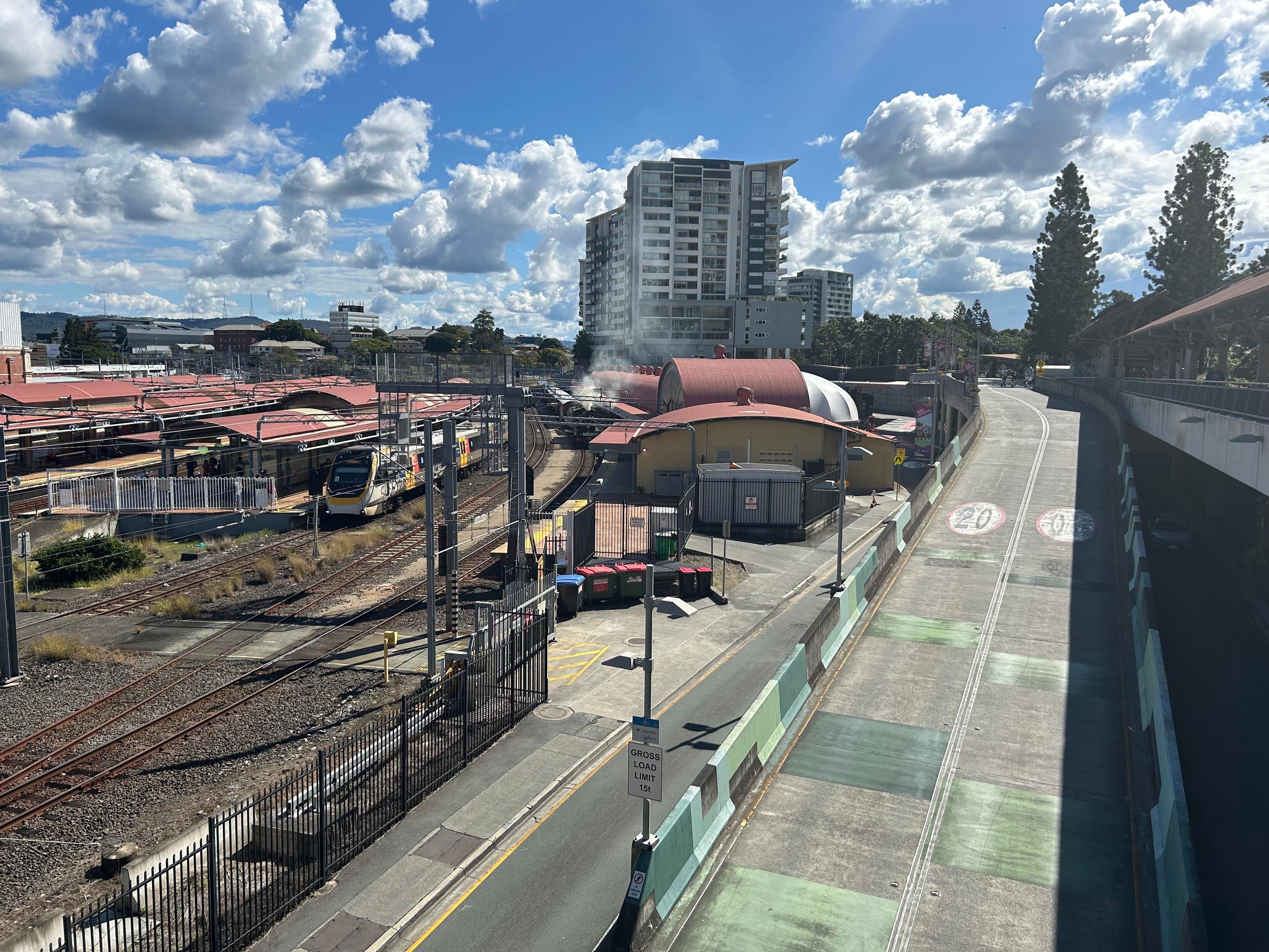 A green steam locomotive stands at platform ten of Roma Street station in Brisbane exhibition grounds, the loco is billowing clouds of brown-grey smoke into the air.