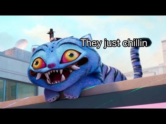 The two best characters from Kpop Demon Hunters: a blue tiger with an enormous grin and large yellow eyes, slightly walleyed, and a magpie with three eyes wearing a fancy hat. They are sitting on the roof of a building and the picture is captioned "they just chillin" 