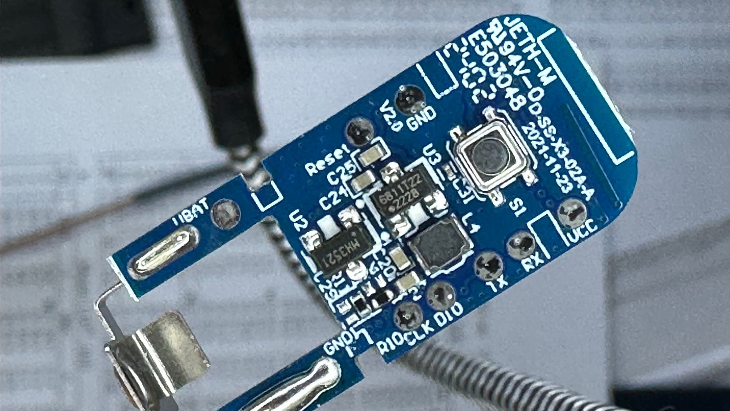 blurry photo of a small circuit board with CLK, DIO, TX, RX, VCC and GND labeled test pads