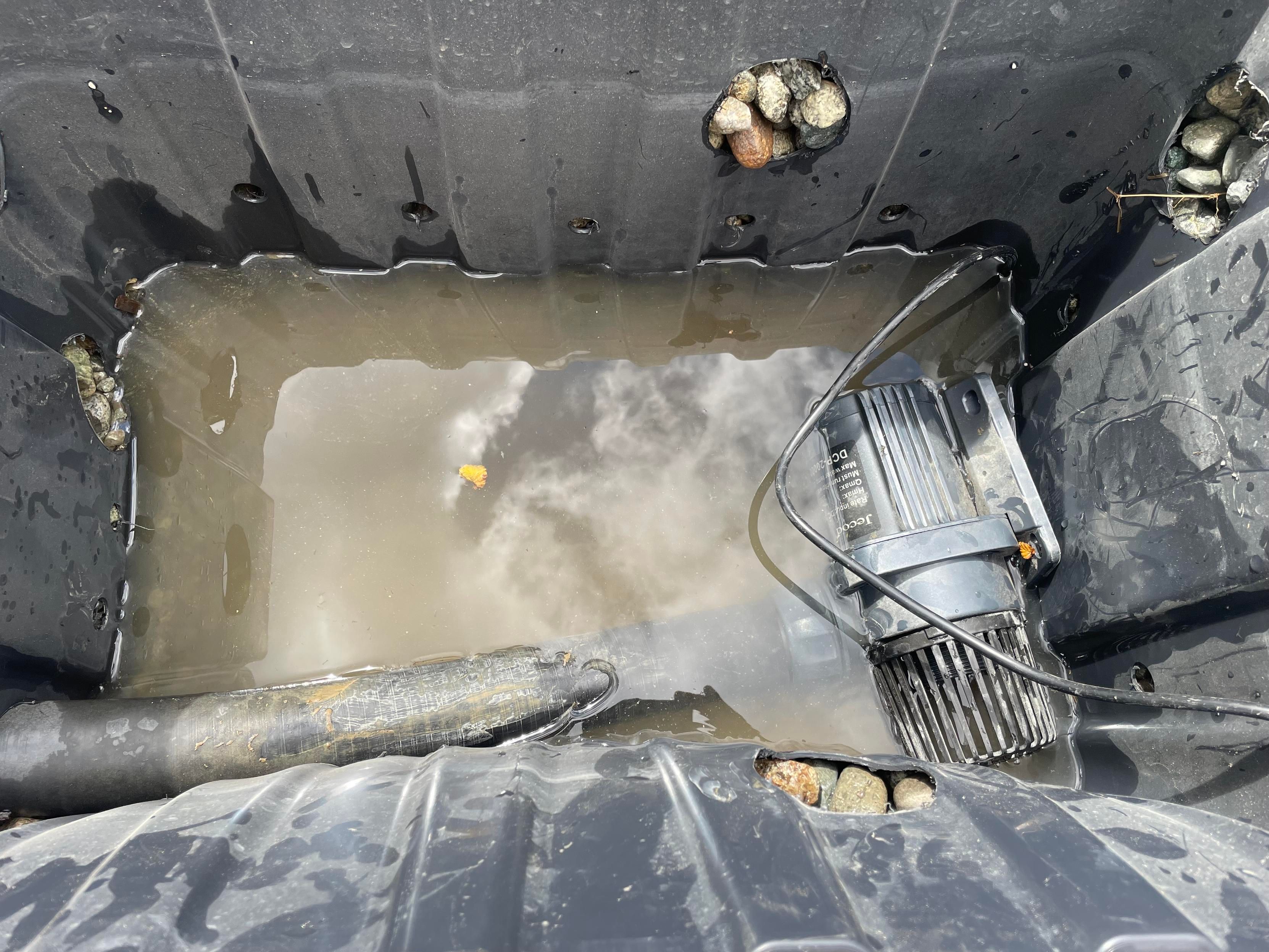 A small pump is on its side in the bottom of a black box. There is a black hose going to it.