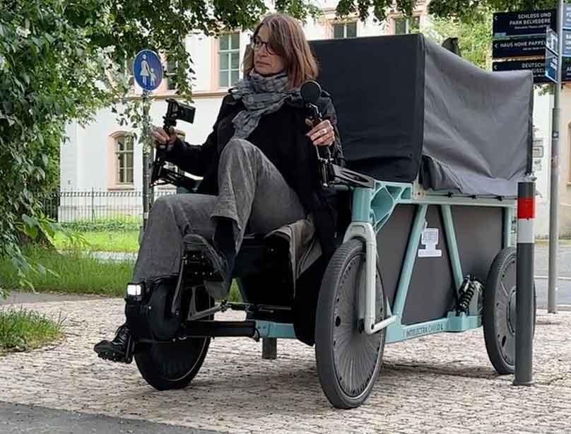 Foto eines Lastenrads von https://dynamic-drives-giessen.com: Die Fahrerin sitzt ganz vorne, quasi vor dem Fahrzeug.