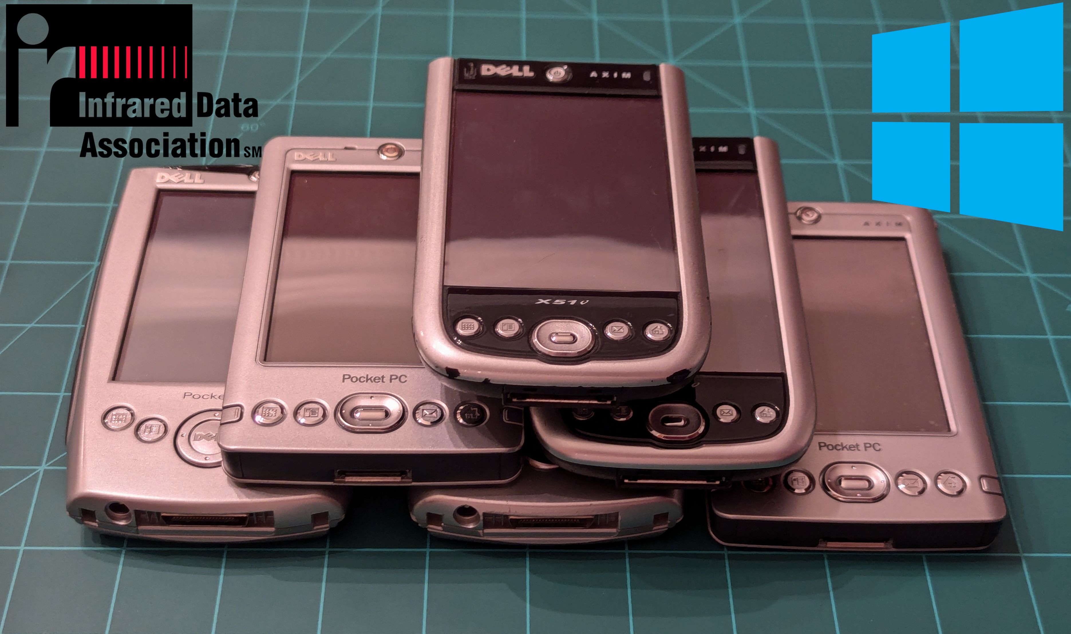 A stack of various Axim Pocket PCs in a pyramid. There is an IrDA and Windows 10 symbol in the top corners. 