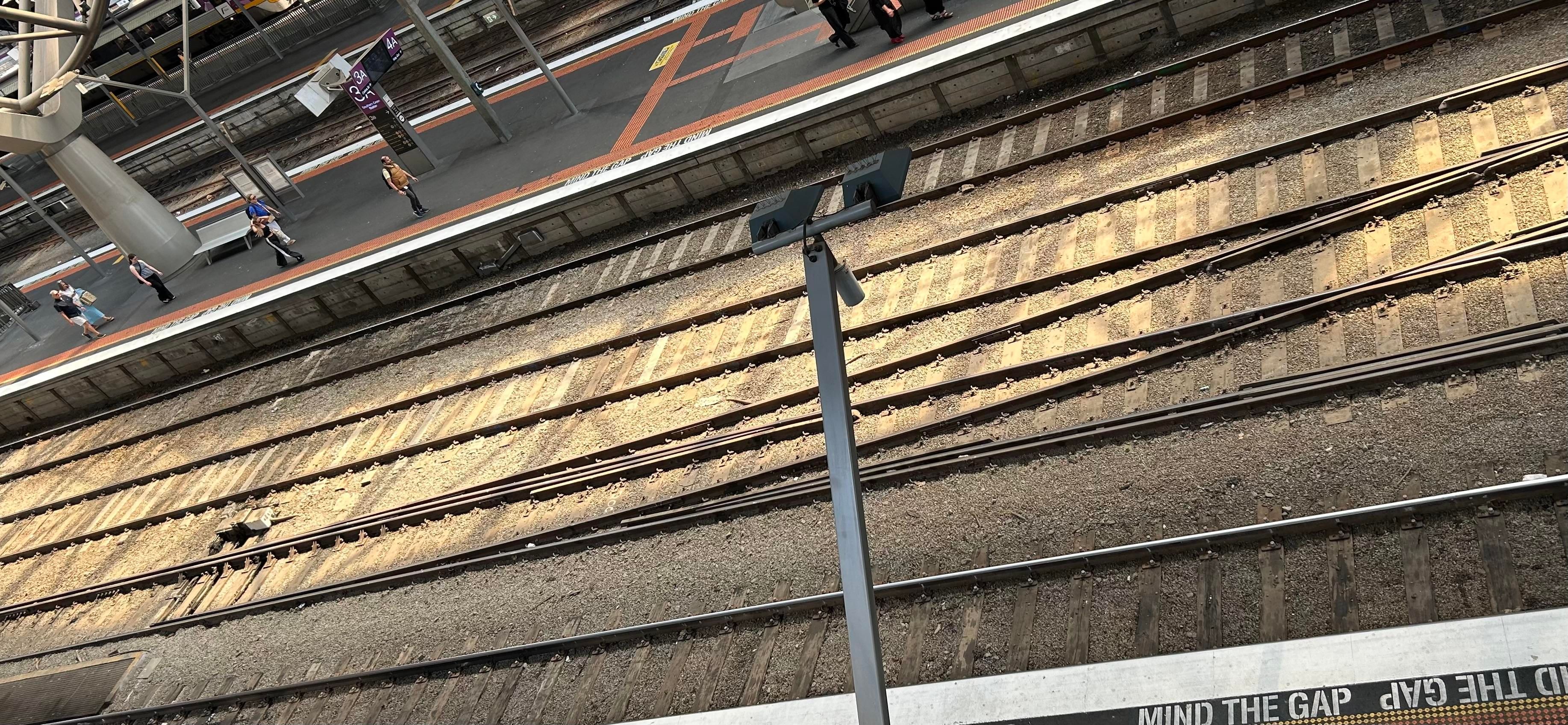 A photo of the railway track formation mentioned in the post, the station is shaded under an overall roof, but some sun is shining through onto the tracks, there are four tracks between two platforms with the closer of the two inner tracks being the dual gauge one where the interesting rail swap occurs.