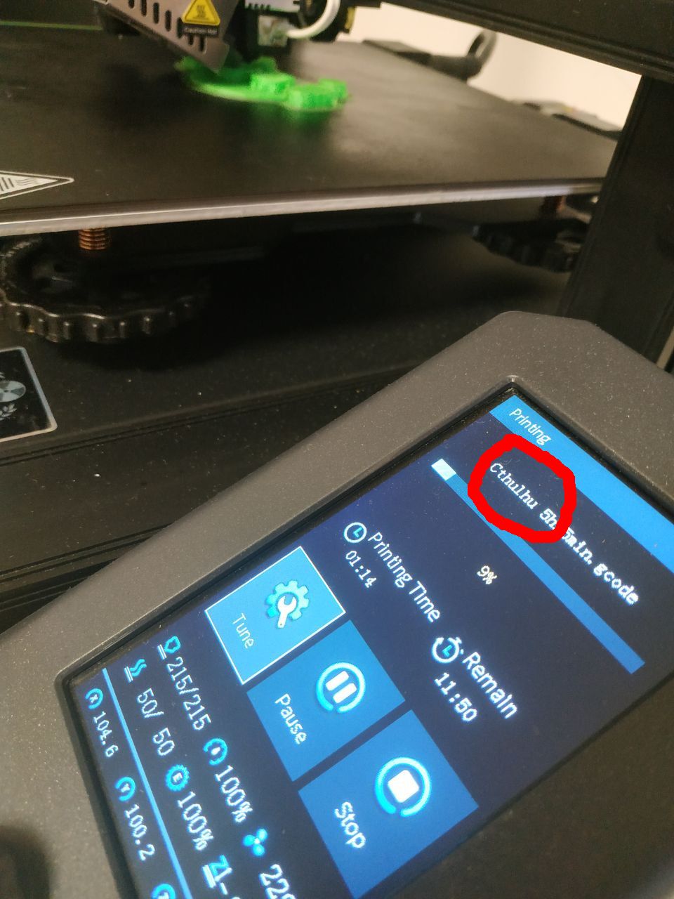 Foto di una stampante 3d all'opera, in primo piano il pannello di controllo coi dati della stampa in corso, il progetto si chiama Cthulhu, sotto i dati dei tempi di stampa, temperatura, velocità e coordinate. Sullo sfondo il piatto di stampa con una forma verde in costruzione.