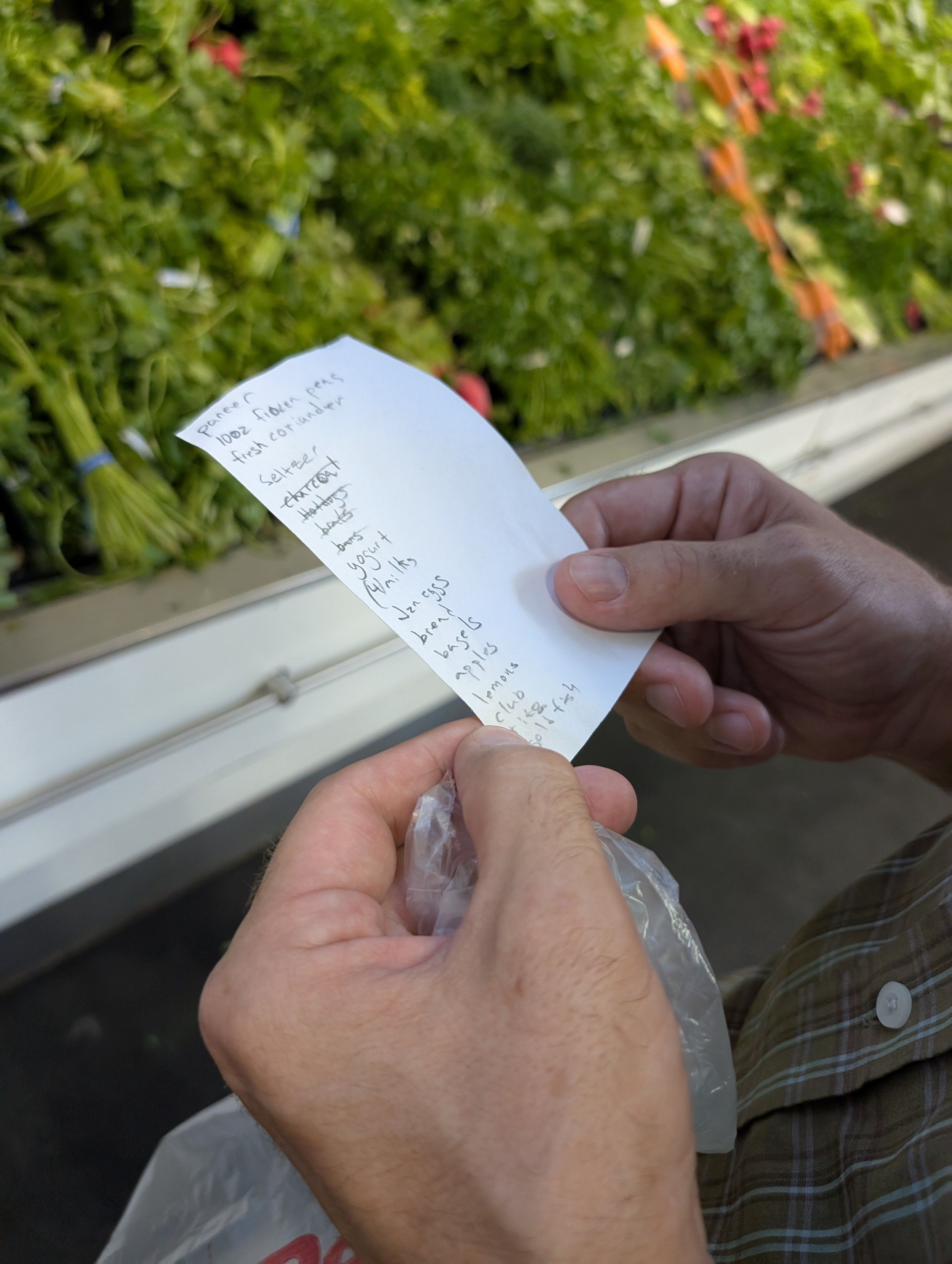 Hands holding a grocery list on a scrap of paper