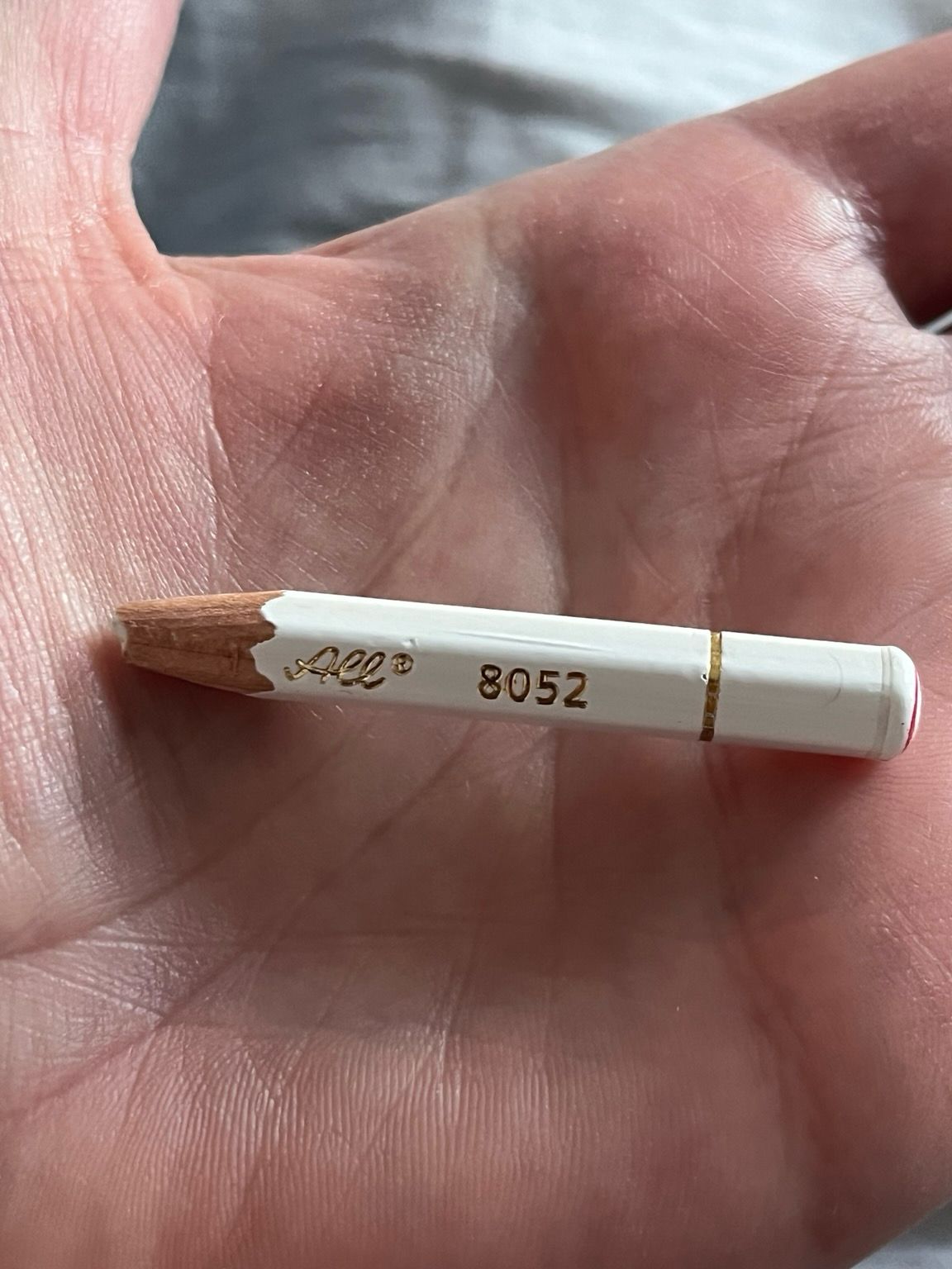 A white pencil sharpened down to a nub. On the side of the pencil are the digits 8052.