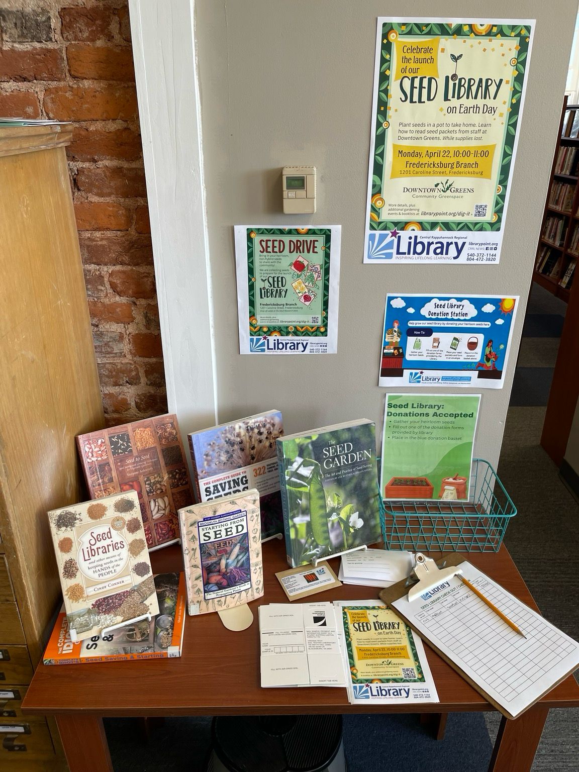 Books on seed libraries, harvesting seeds, and various fliers announcing the seed library. 