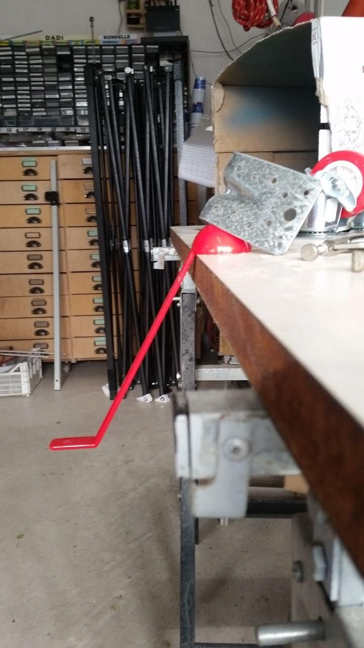 Mestolo in plastica rossa appoggiato su un tavolo.
Il manico è inclinato a 30°.