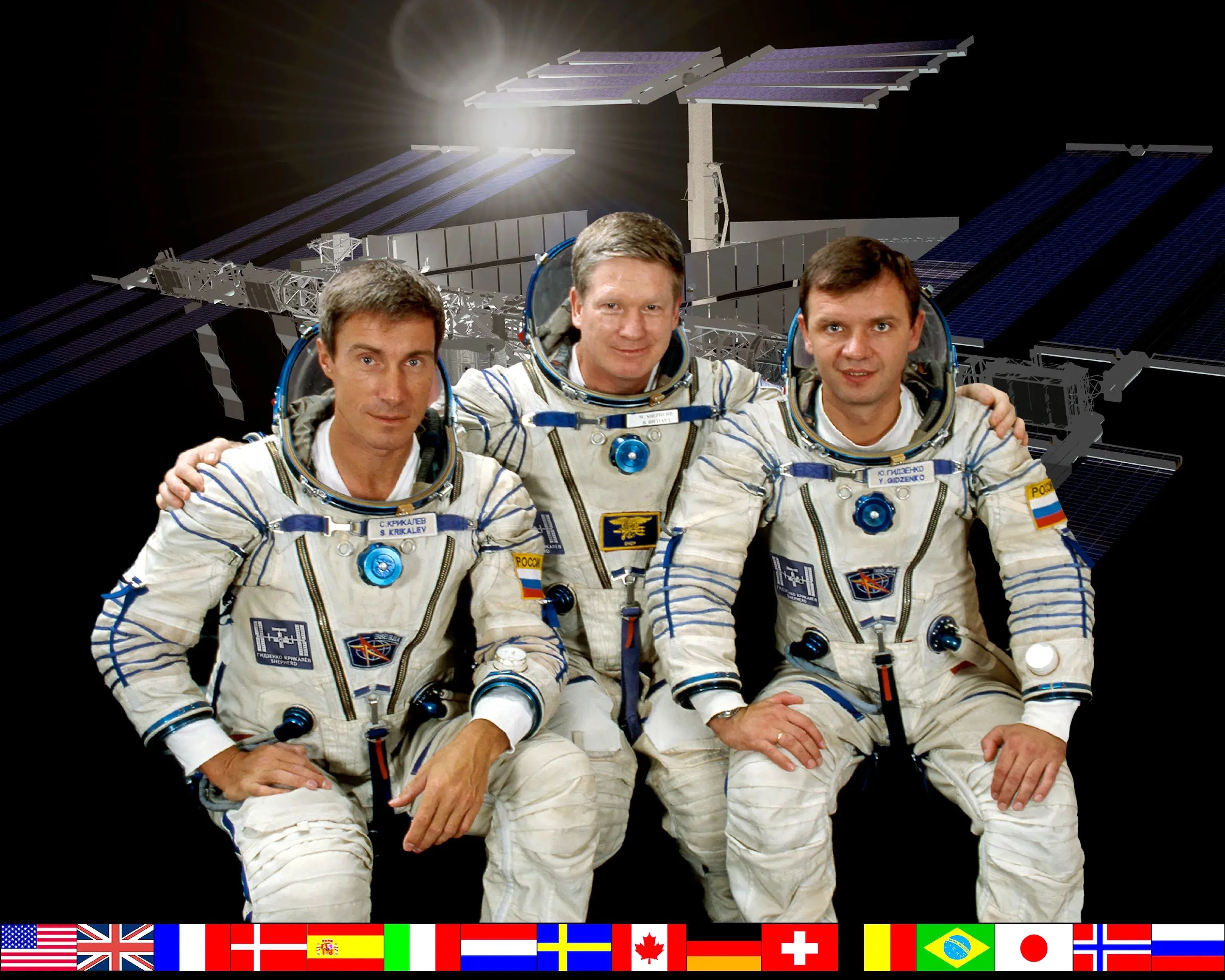 Official portrait of the Expedition 1 crew

ISS01-S-002 or JSC2000-06243 (October 2000) --- ISS Expedition One Commander William M. (Bill) Shepherd (center) is flanked by Soyuz Commander Yuri P. Gidzenko (right) and Flight Engineer Sergei K. Krikalev (left) in this crew photograph, taken during a break in training in Russia. The three, posed in front of a rendition of the International Space Station, are wearing the Sokol space suits like those they will don for their Soyuz-provided trip to ISS later this month. National flags representing all the international partners run along the bottom of the portrait.
Image Credit: NASA