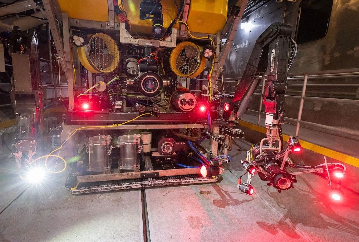 Large robot with lots of red lights and what looks like a grabby arm