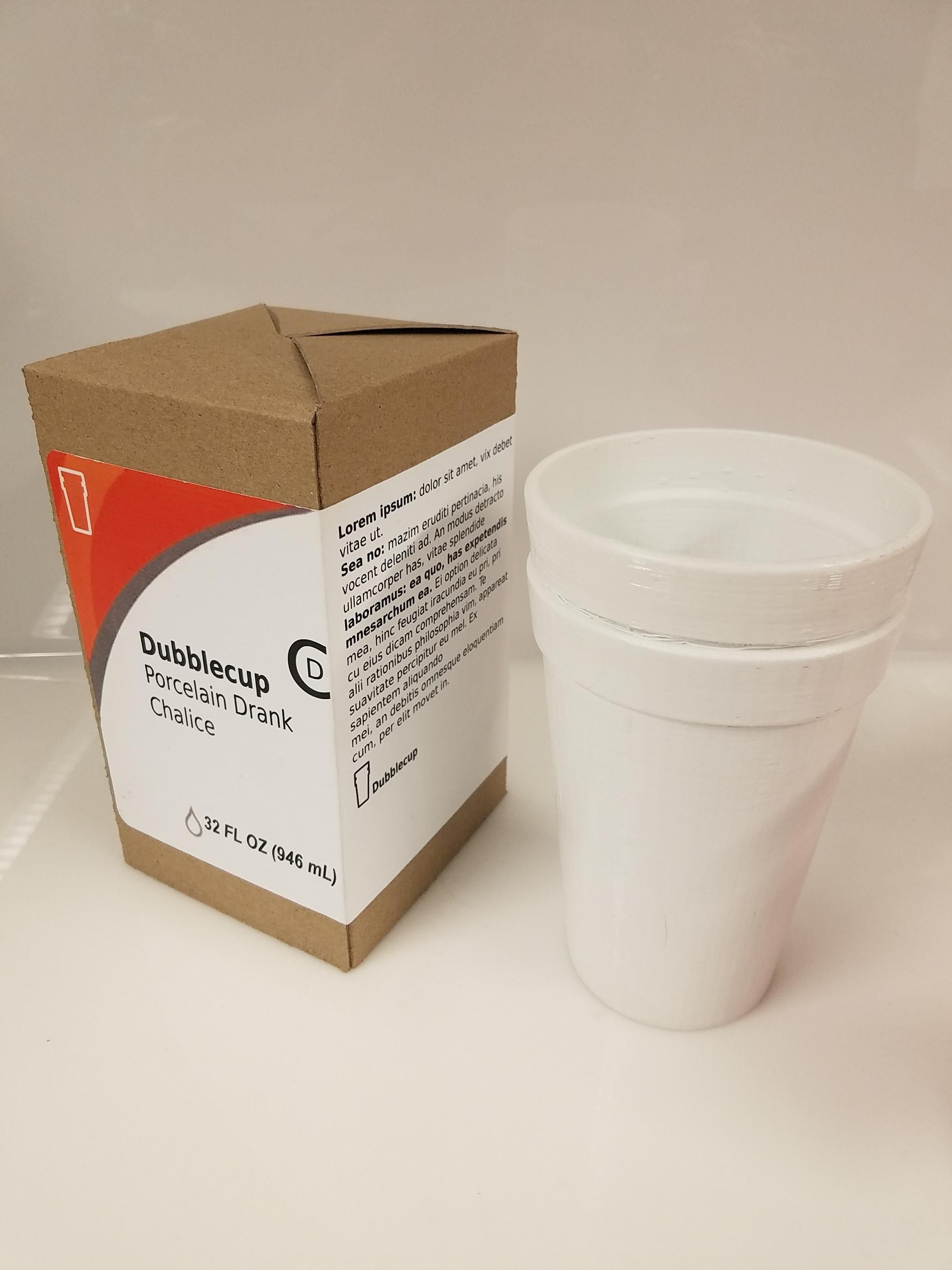 A brown chipboard packaging mockup with a label that reads "Dubblecup porcelain drank chalice" featuring lorem ipsum on the side. Next to it, a white 3D-printed facsimile of stacked foam cups. 