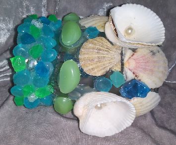 Glass jar with blue and green acrylic gems, sea shells, faux pearls, and green glow in the dark stones.