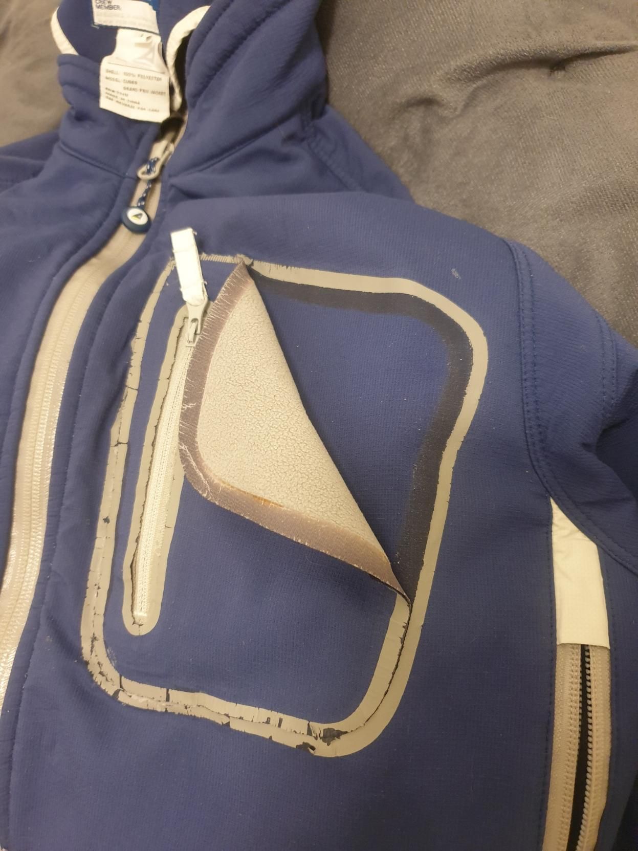 Waterproof jacket with a chest pocket peeling off after going through the dryer. It had been sealed on with some kind of tape for a nice waterproof seal.