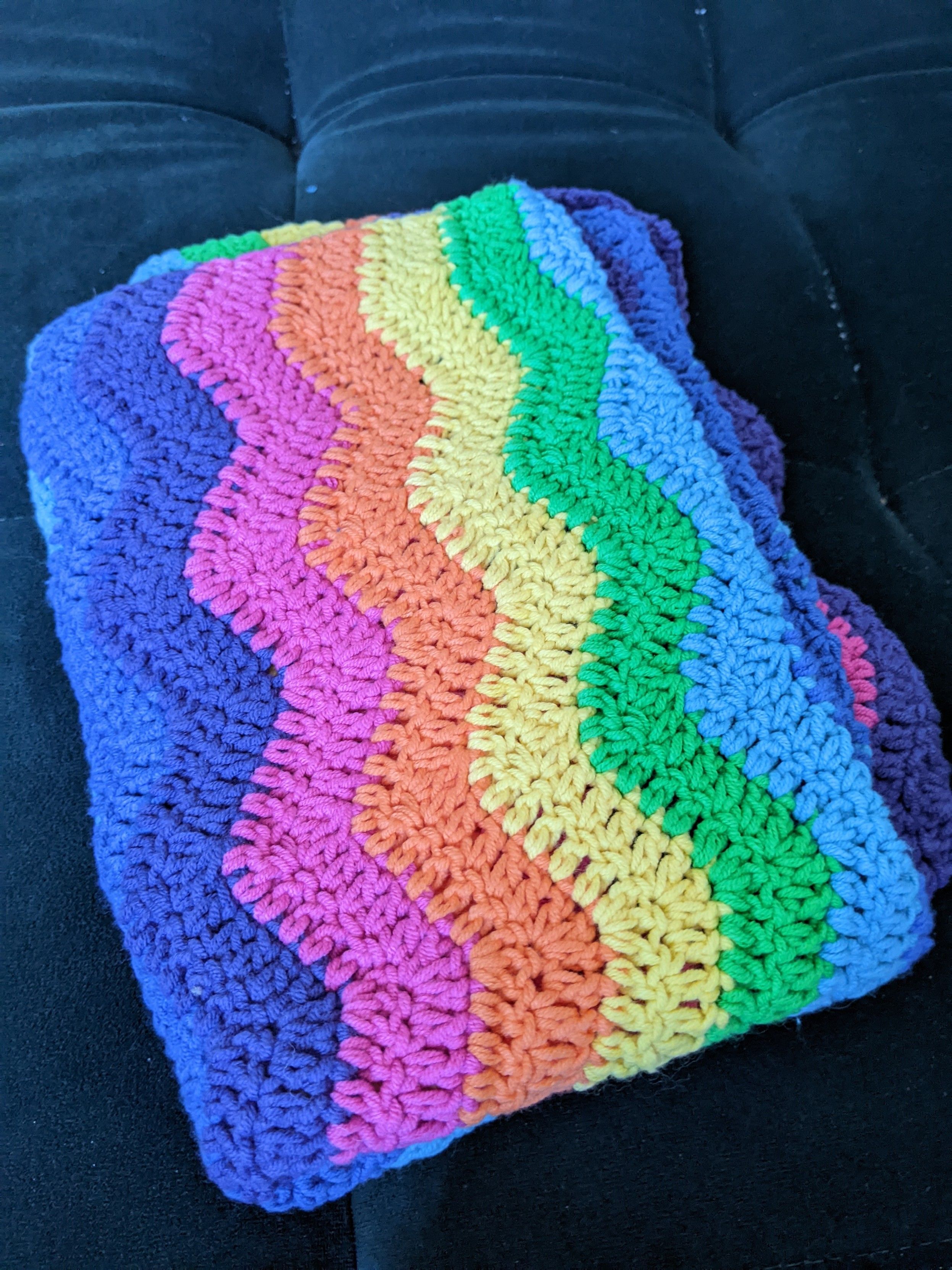 Une couverture pour bébé faite au crochet avec des rayures en zigzag, en fil de coton multicolores