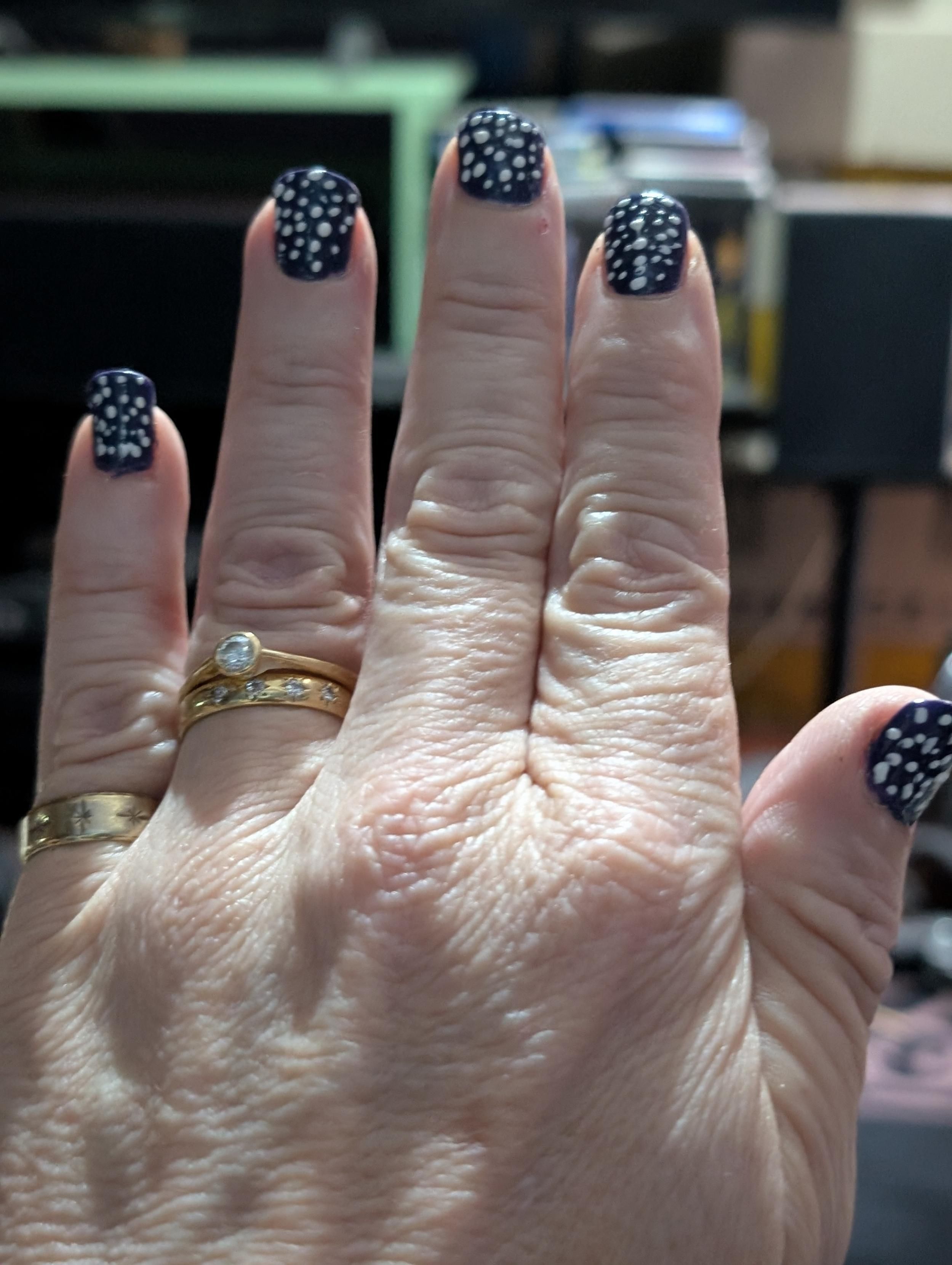 My hand with four fingers showing with nail polish in purple and today, white dots have been added