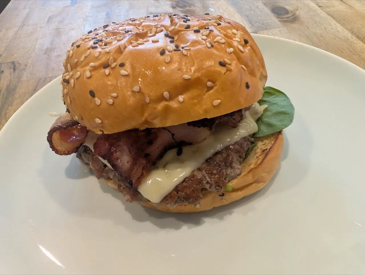 a burger with a meat patty, cheese spinach and bacon