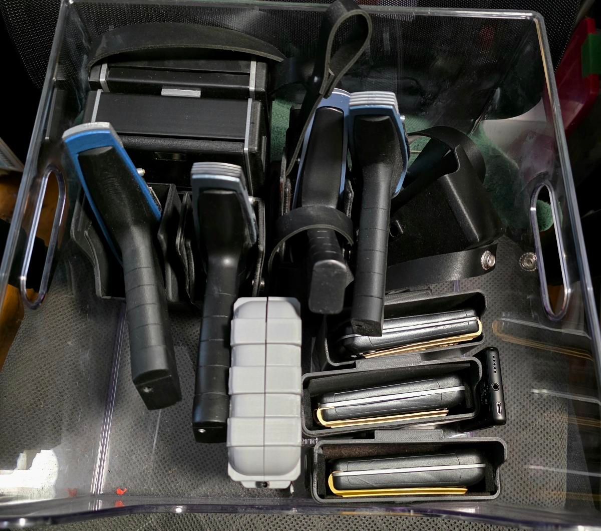 A bin full of Star Trek Strange New worlds props. Four phasers, two tricorders, and four  communicators (One is in a grey case)