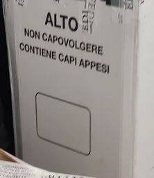 una scatola con scritto "ALTO - NON CAPOVOLGERE - CONTIENE CAPI APPESI"
