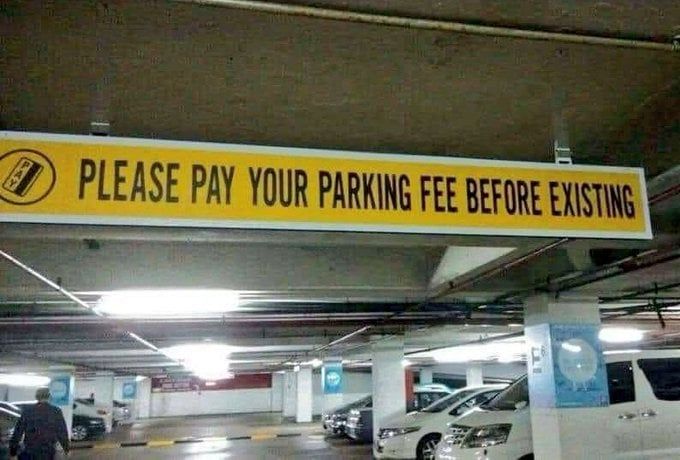 A sign in a parking garage which says, "Please pay your parking fee before existing."