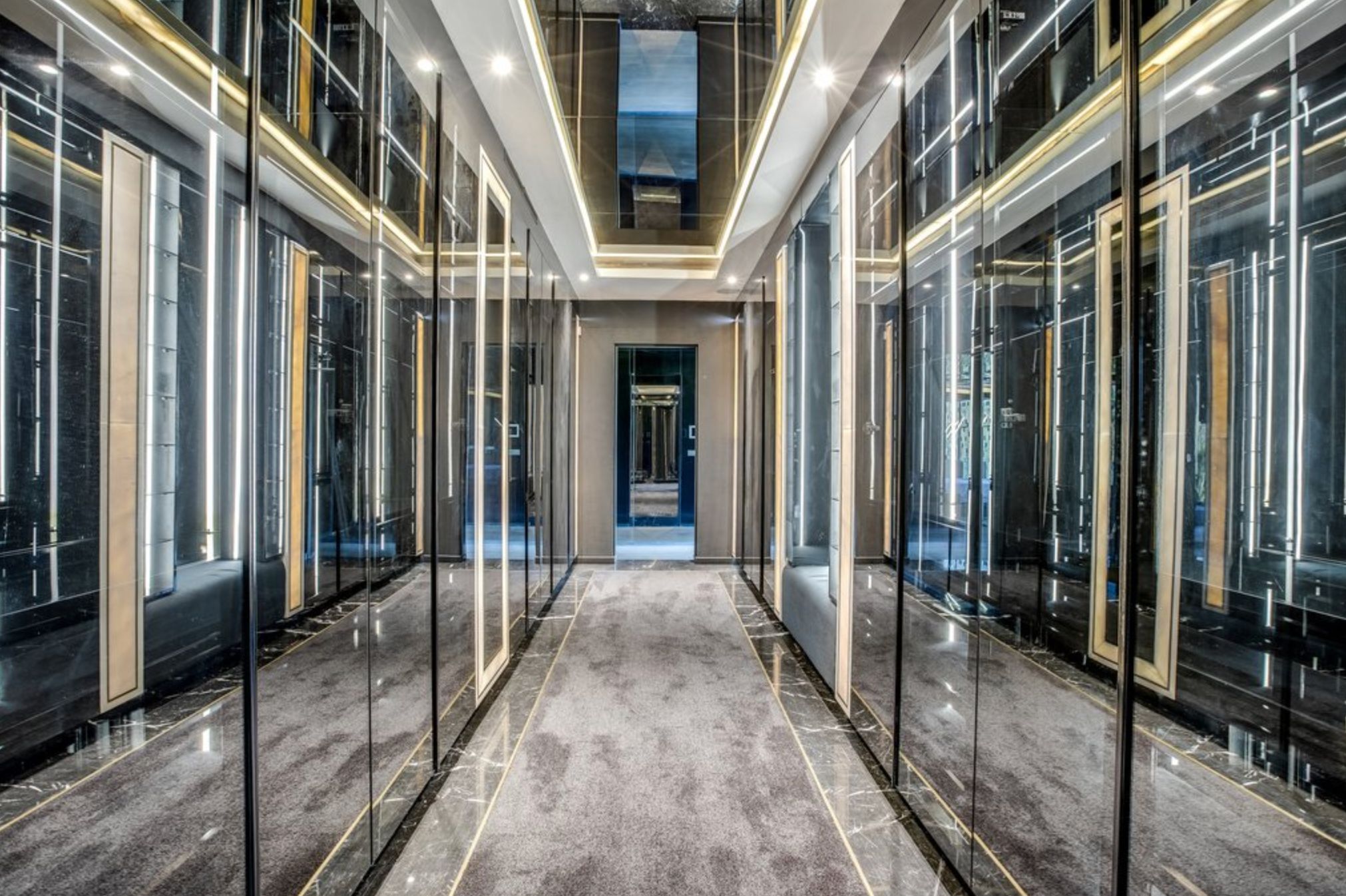 A closet with mirrored doors and ceiling with panels of LED strip lighting and the whole thing is very reflective and confusing. 