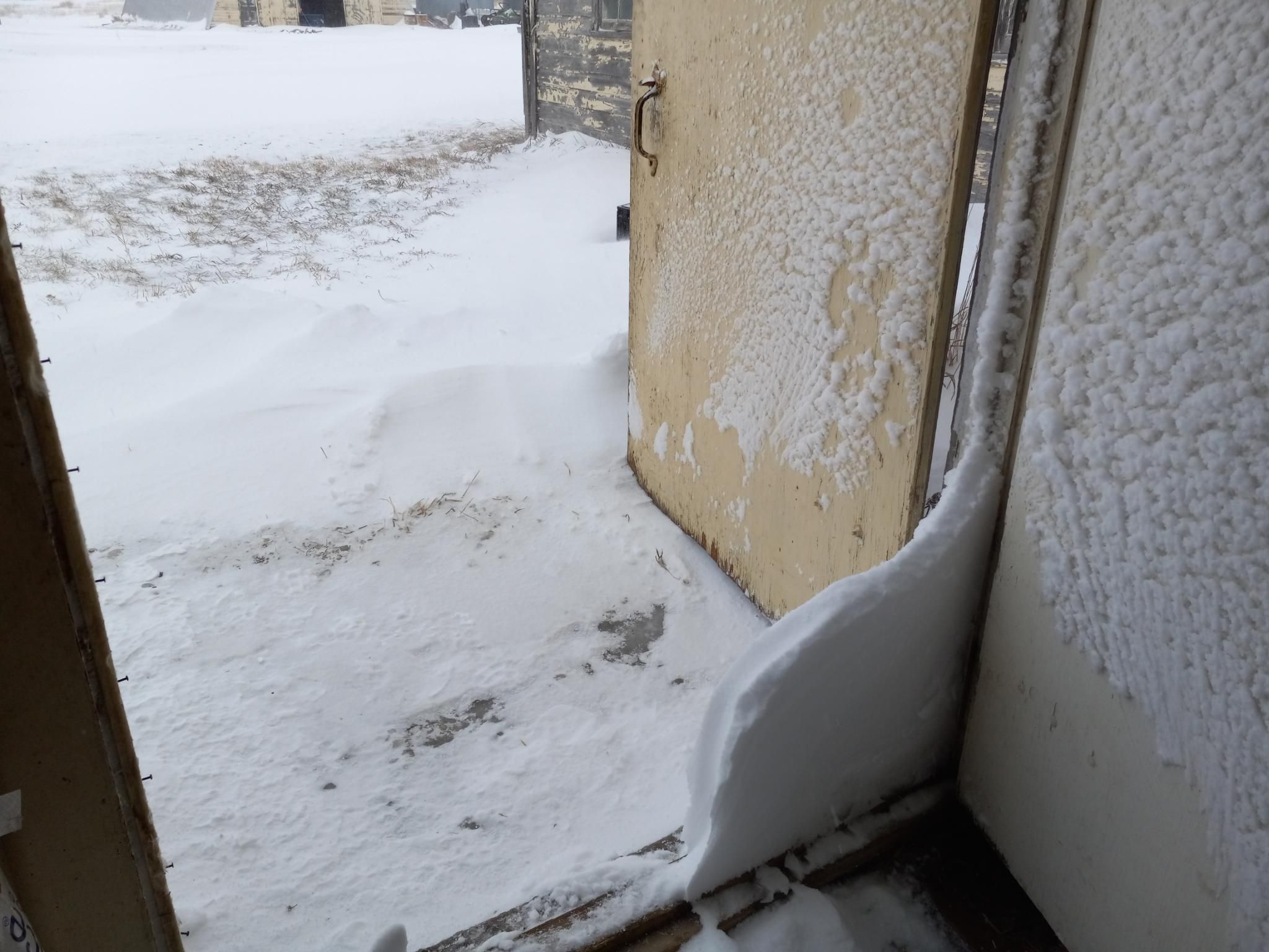 A weird slice of snow that built up in between an outer door and an inner door.  It's about 3 inches thick and maybe 1 foot tall.  It's very snowy outside the door.