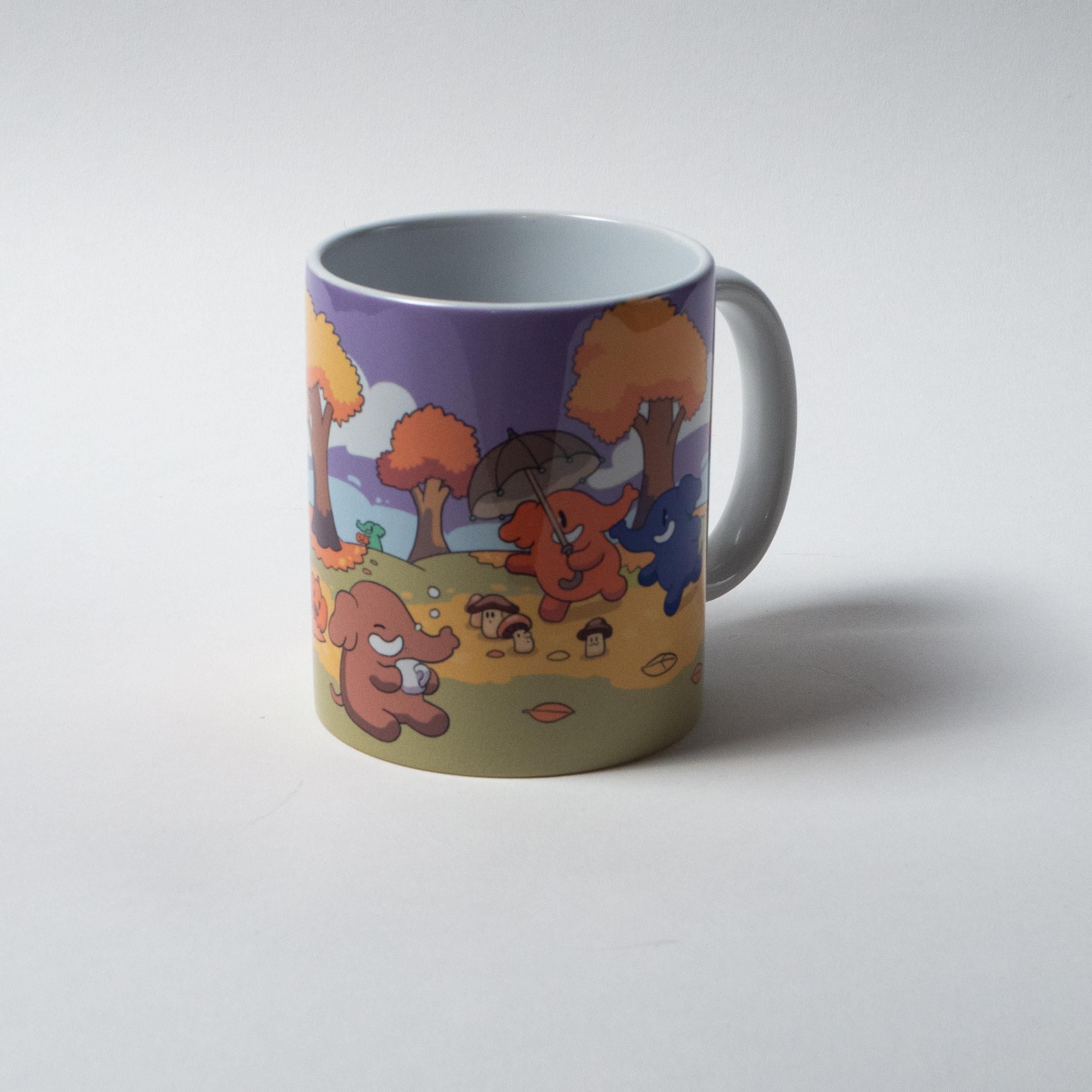 A ceramic mug with a colorful print on it, featuring a blue and a peach colored Mastodon walking under auburn trees, surrounded by mushrooms. One of them is holding an umbrella. Another Mastodon is sitting with a mug of hot beverage.