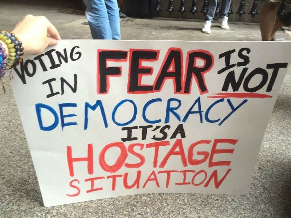 Sign reads: VOTING IN FEAR IS NOT DEMOCRACY IT'S A HOSTAGE SITUATION