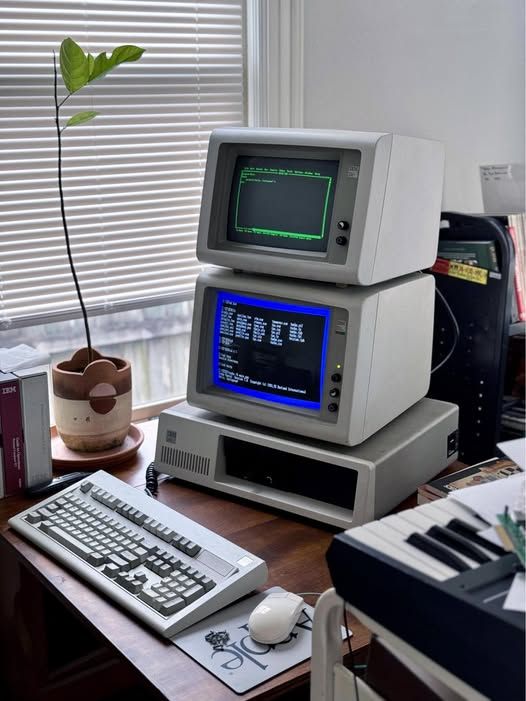 AI Generated image of IBM PC XT clone (8086 CPU) with two 14 inch CRT monitors one on top of the other above the computer desktop chassis. Both show some command line interface, one is MS DOS, the other one probably a terminal emulator.