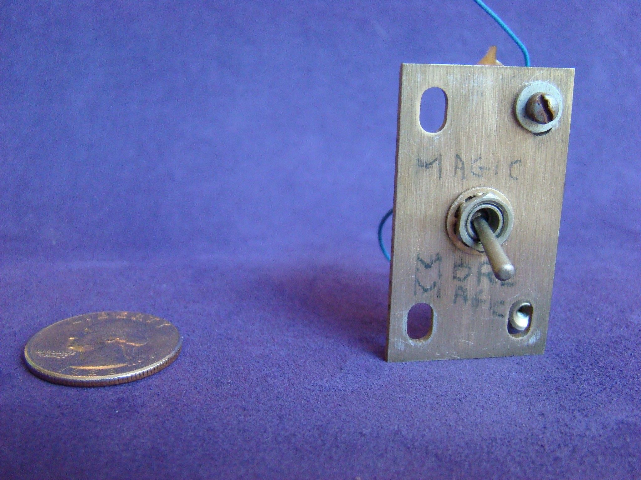 An old toggle switch attached to a blanking plate. On the plate some words have been written in marker. 
 
Above the switch is written, “MAGIC” and below the switch is written “MORE MAGIC”. 
 
The switch is in the “MORE MAGIC” position.