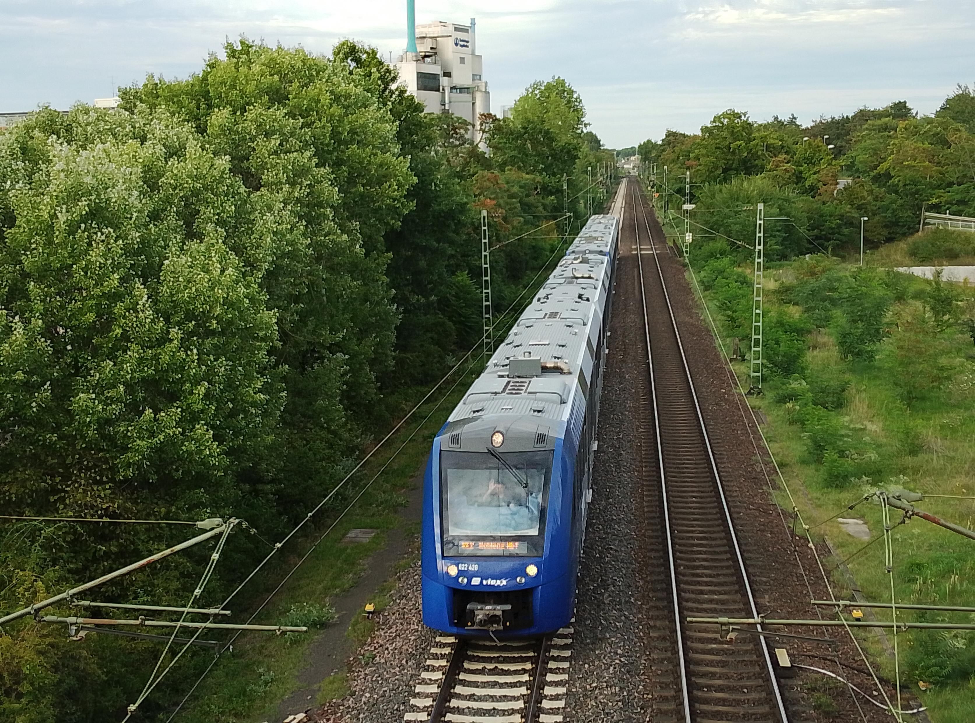 A blue electric train passes under the bridge I'm crossing. 