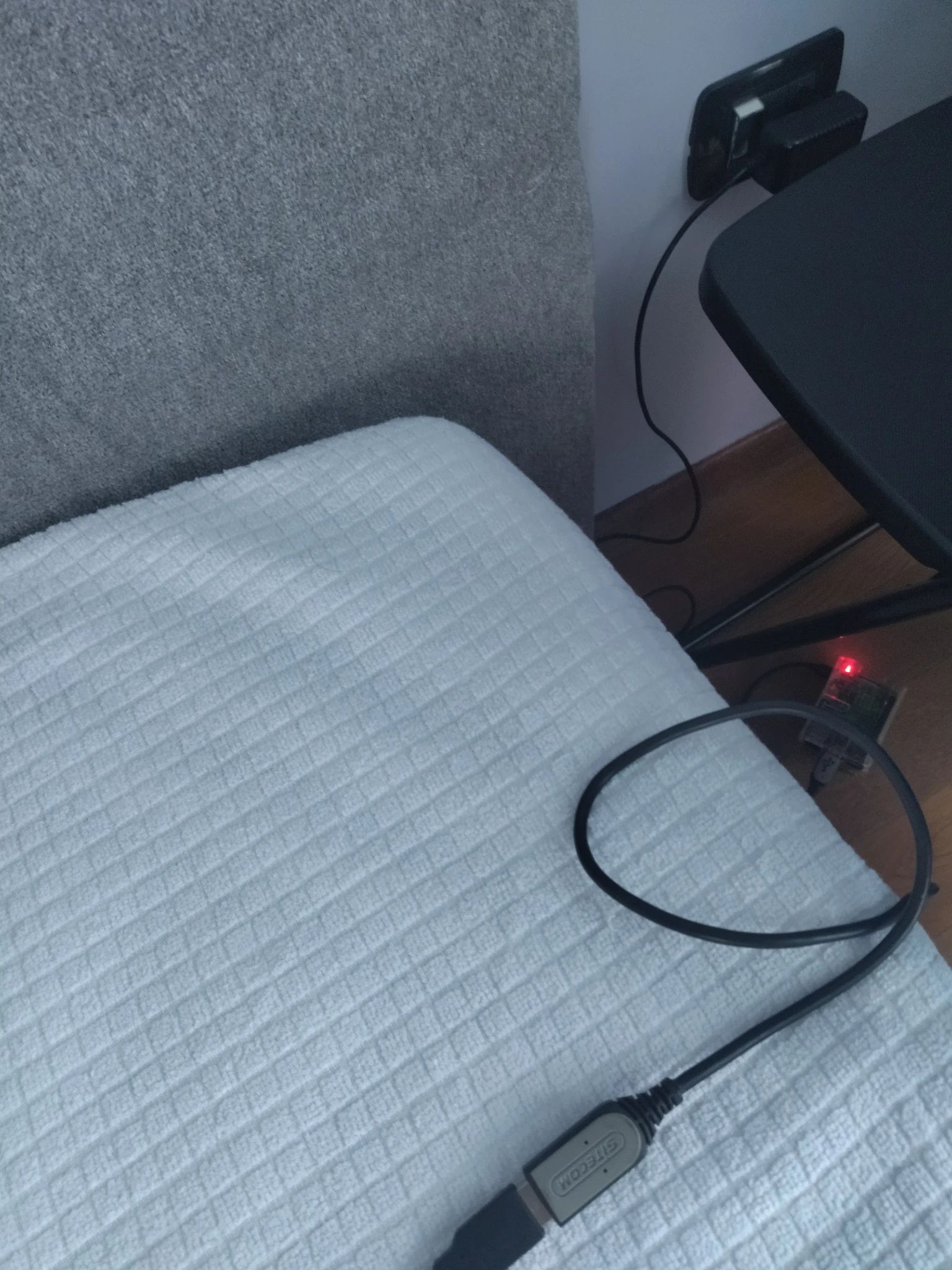 Foto più da dentro il letto, con il filo che viene dalla tastiera che si vede che va giù per terra, dove si intravede il Raspberry, collegato alla presa subito sopra