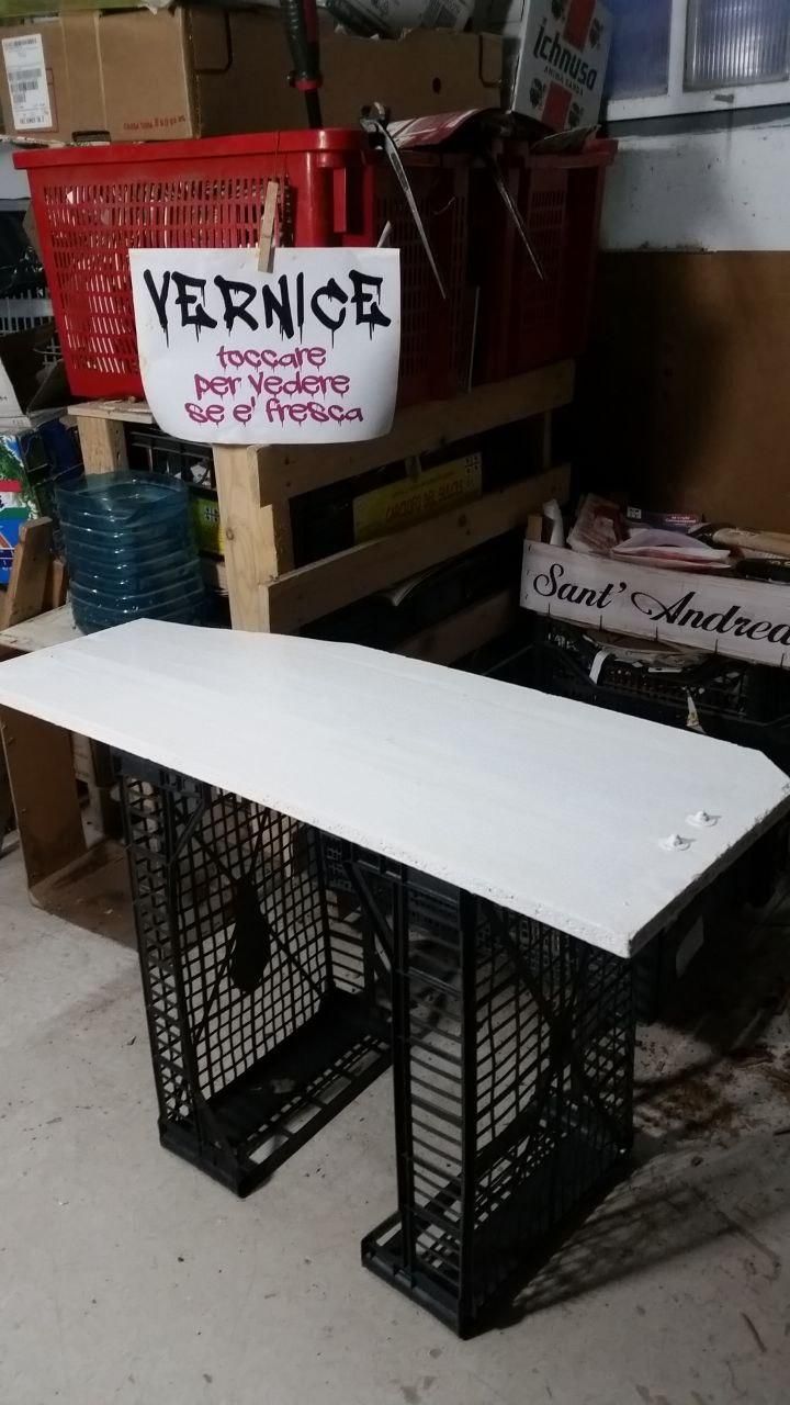 Pannello appena verniciato, appoggiato su due cassette di plastica per verdura, con cartello: "VERNICE - toccare per vedere se è fresca".
