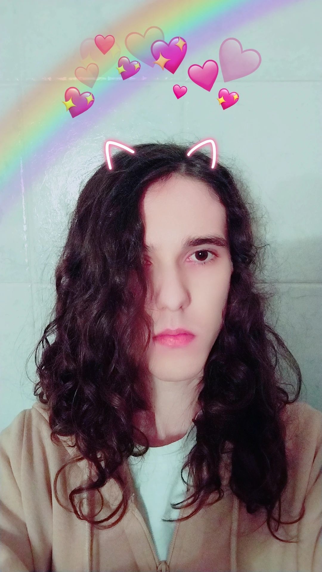 Selfie in bagno come descritto, decorato con B612. Sticker di orecchie vagamente da gatto neon in testa, cuoricini vari un po' più sopra alla testa, con un arcobaleno che li trapassa.