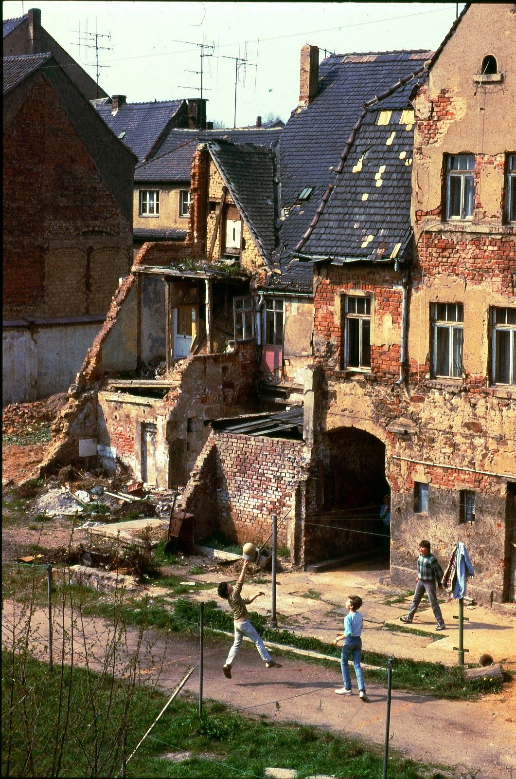 Teenagers playing in front of partially demolished houses.