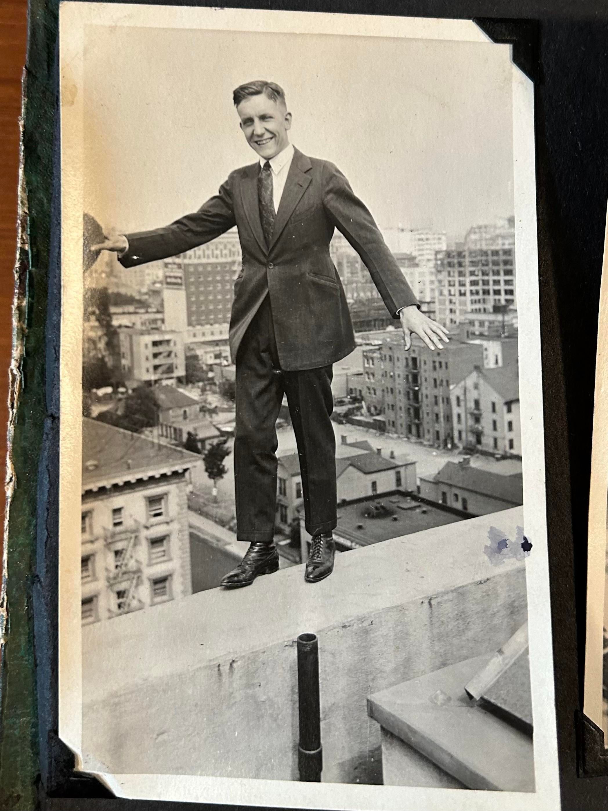 My grandfather, in his mid-20s, probably taken in the early 1920s, wearing a suit and tie, balancing on the parapet of a building several stories above a city street. Maybe Vancouver? Not sure.