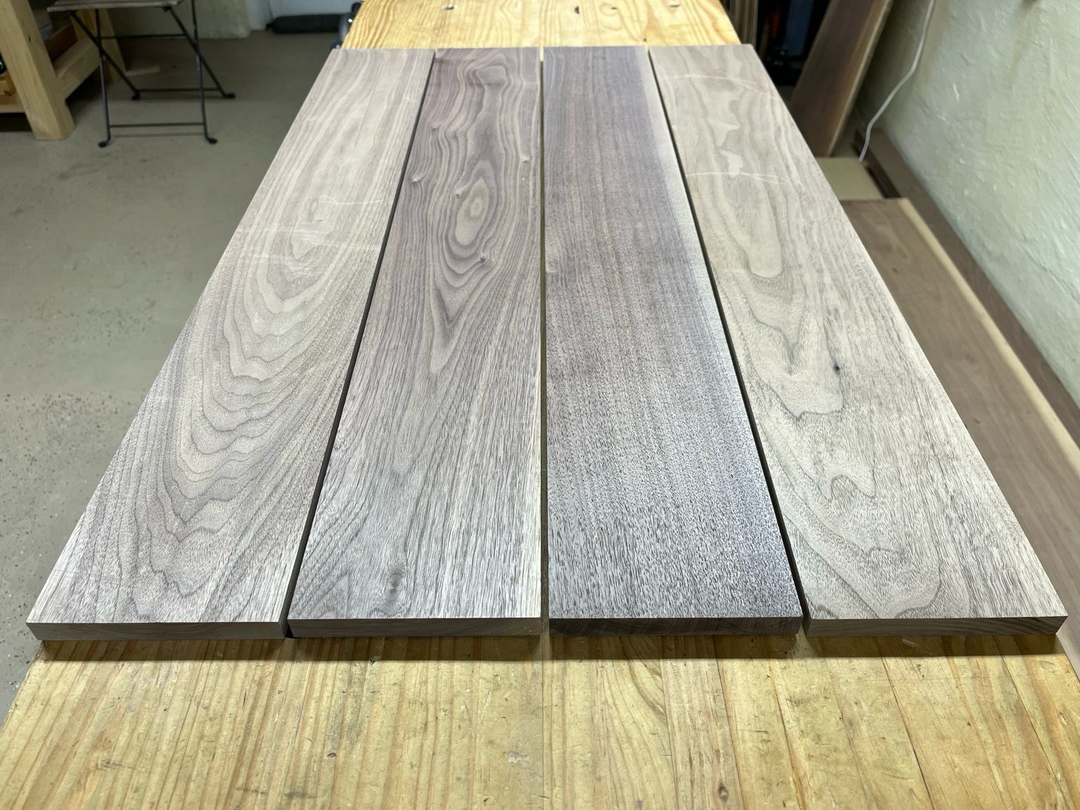 Four walnut boards laying side by side with a quarter inch gap between them. It’s showing the boards before clamping.