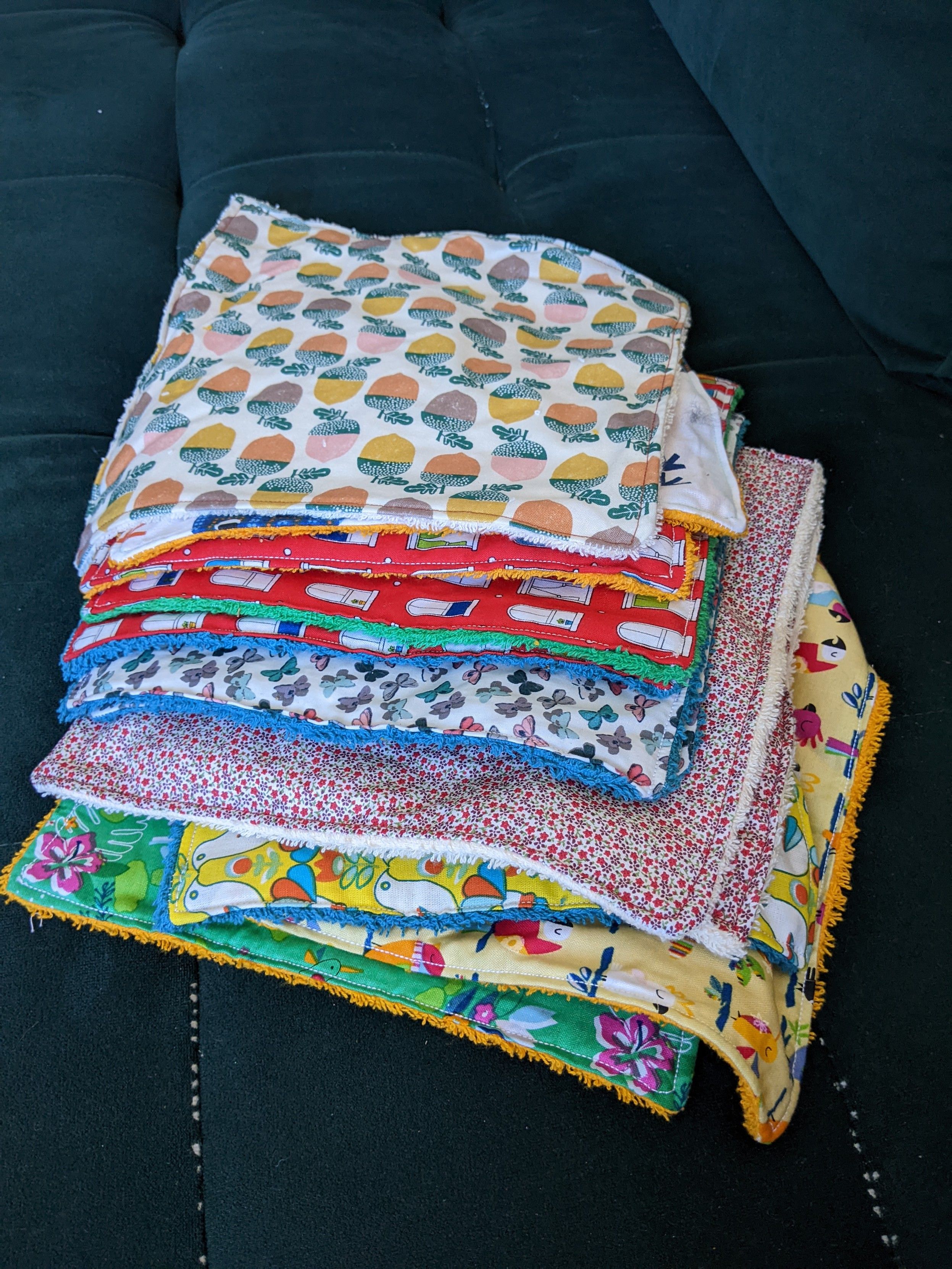 Pile de serviettes de table faites maison : une face coton imprimé coloré, une face unie en coton éponge de couleur assortie.