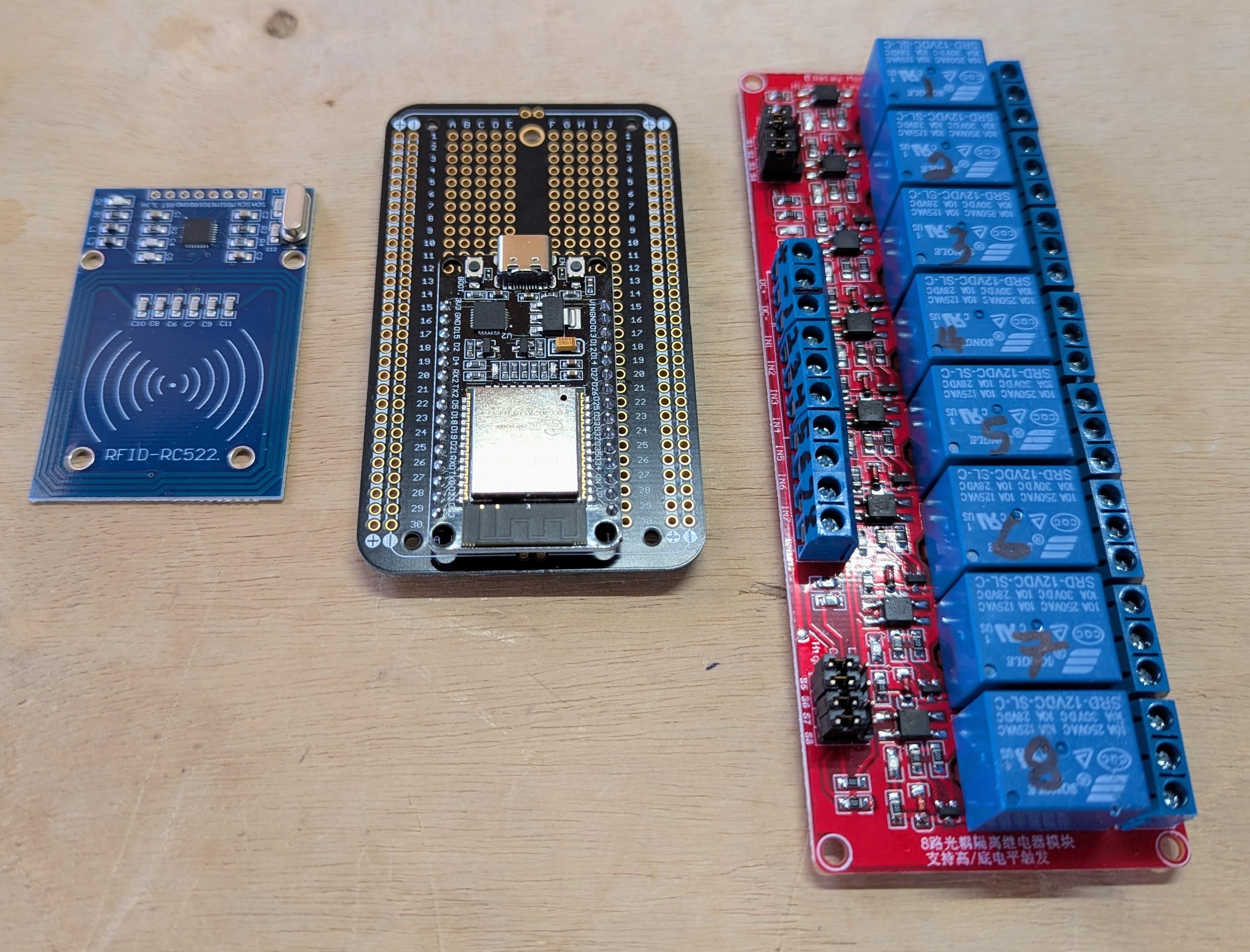 A photo of a RFID reader, a small microcontroller dev board, and a board with eight relay switches.