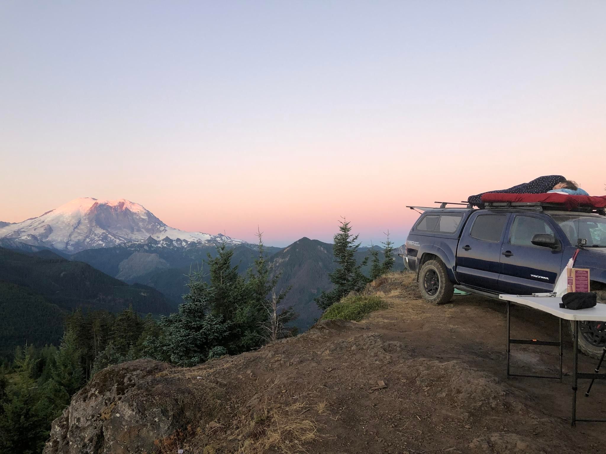 Photo at dawn of me sleeping on my truck overlooking a valley near Mt. Rainier