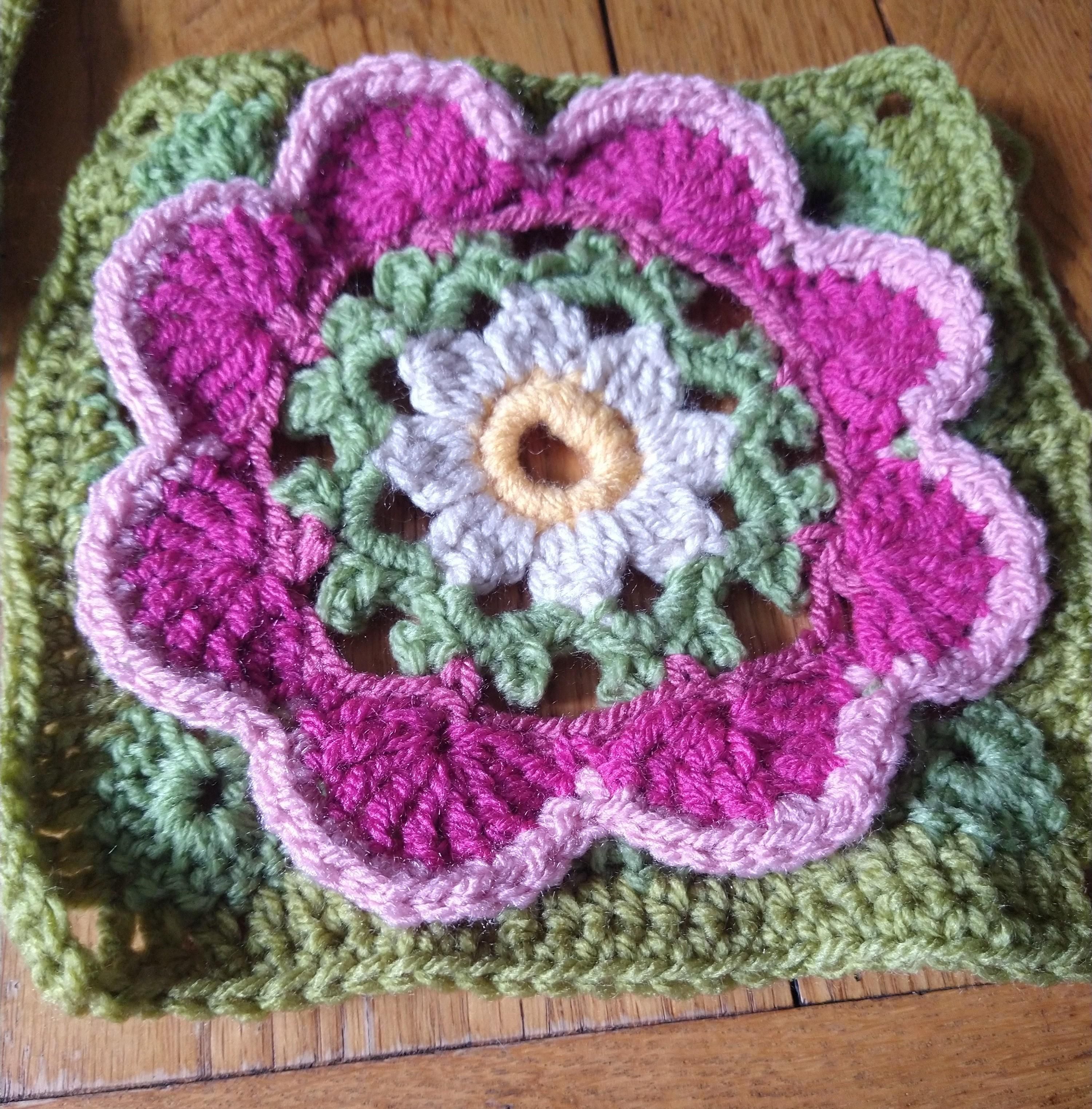Single crochet flower motif with pink flower shape centres and green borders 