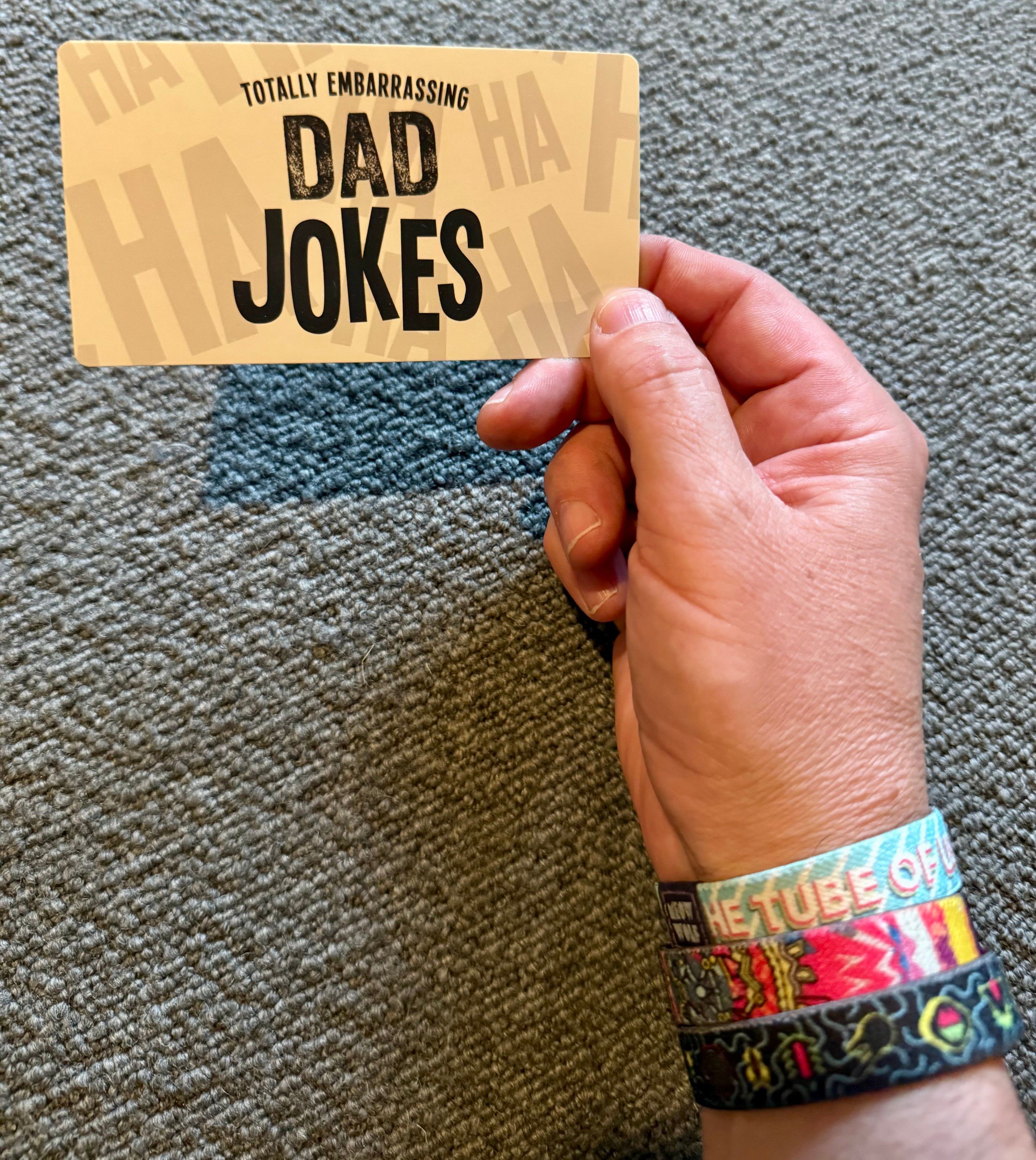 Hand holding a “totally embarrassing Dad Jokes” card