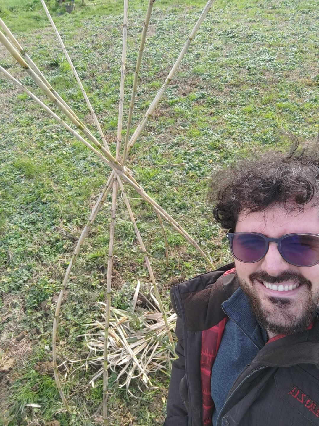 Gabriele Primavera sorridente davanti la una quercia sughera posta sotto una struttura di cannucce e pacciamata con il fogliame degli stessi