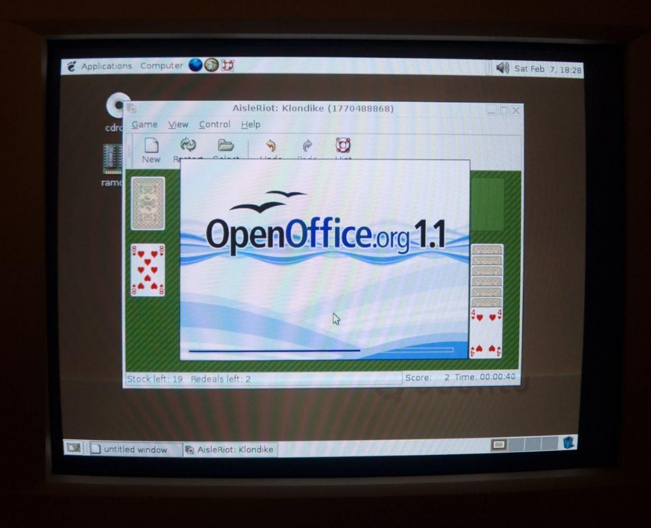 A photo of a CRT: Open Office 1.1 splash screen on top of a Gnome solitaire Aisleriot