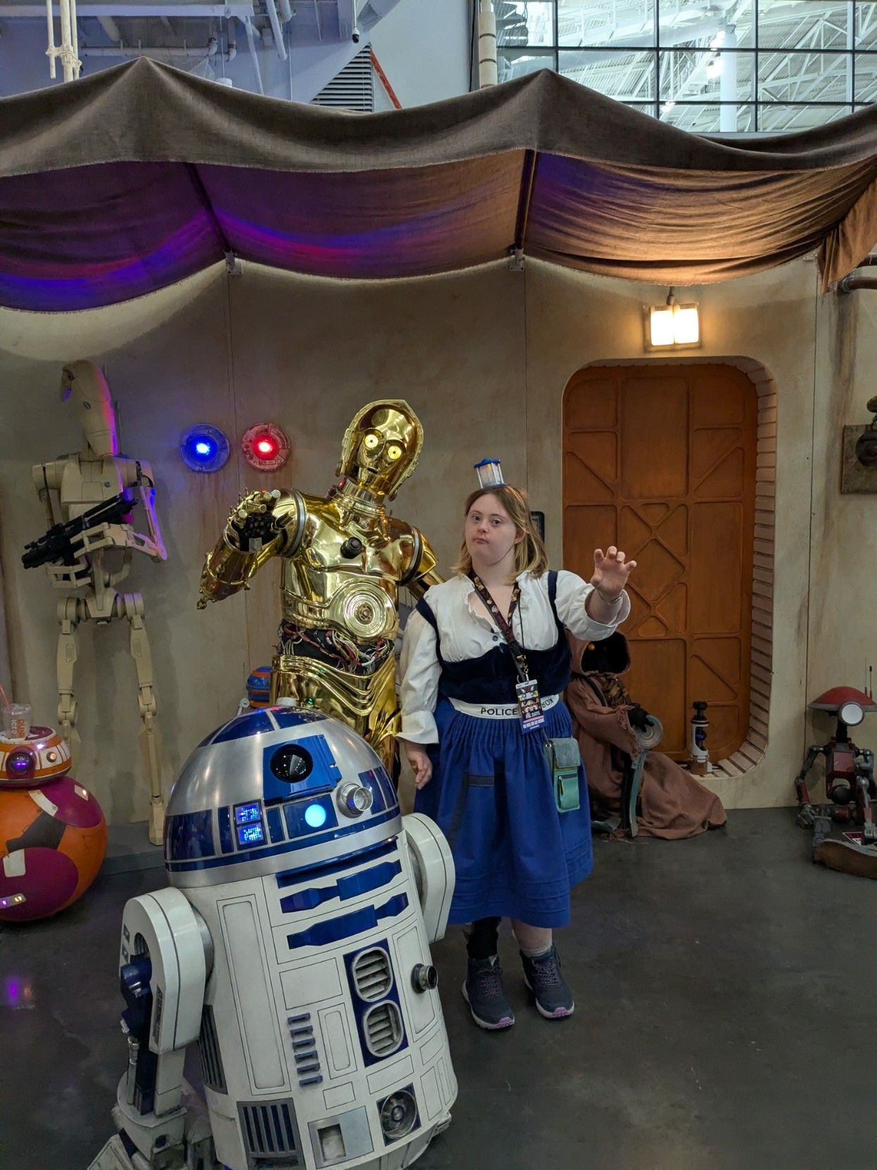 A young woman with Down syndrome dressed up as a TARDIS standing next to C3-PO and R2D2