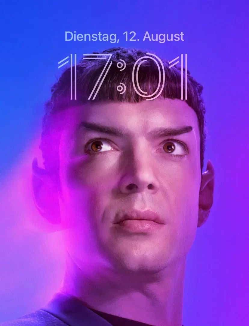 Screenshot of an iPhone homescreen, cropped.
The background image is a promo photo of Ethan Peck as Spock. He's looking the the top left, the background is purple.
The date is just above his head, and the time below it says: 17:01.
