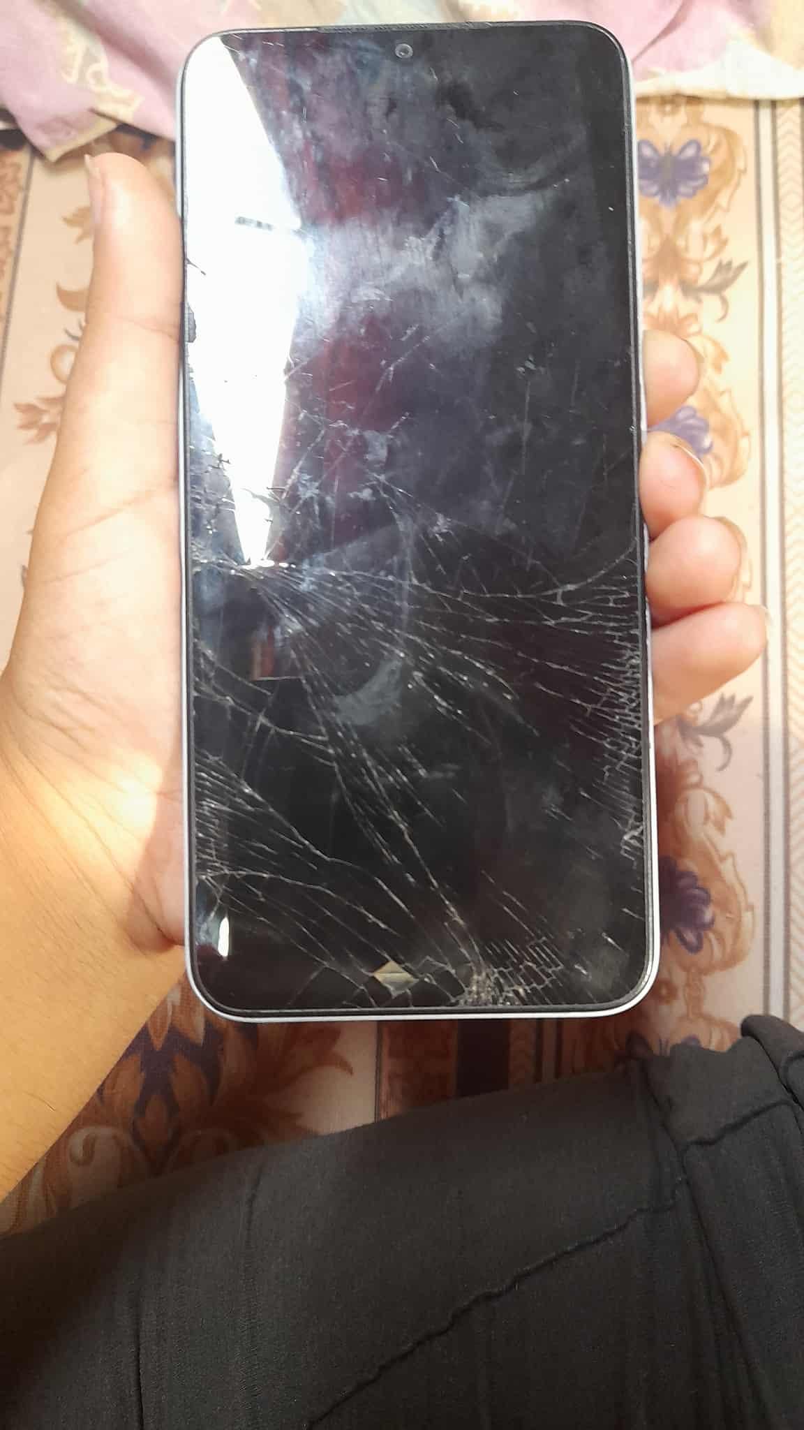 Naeema's holding a phone with a shattered screen.