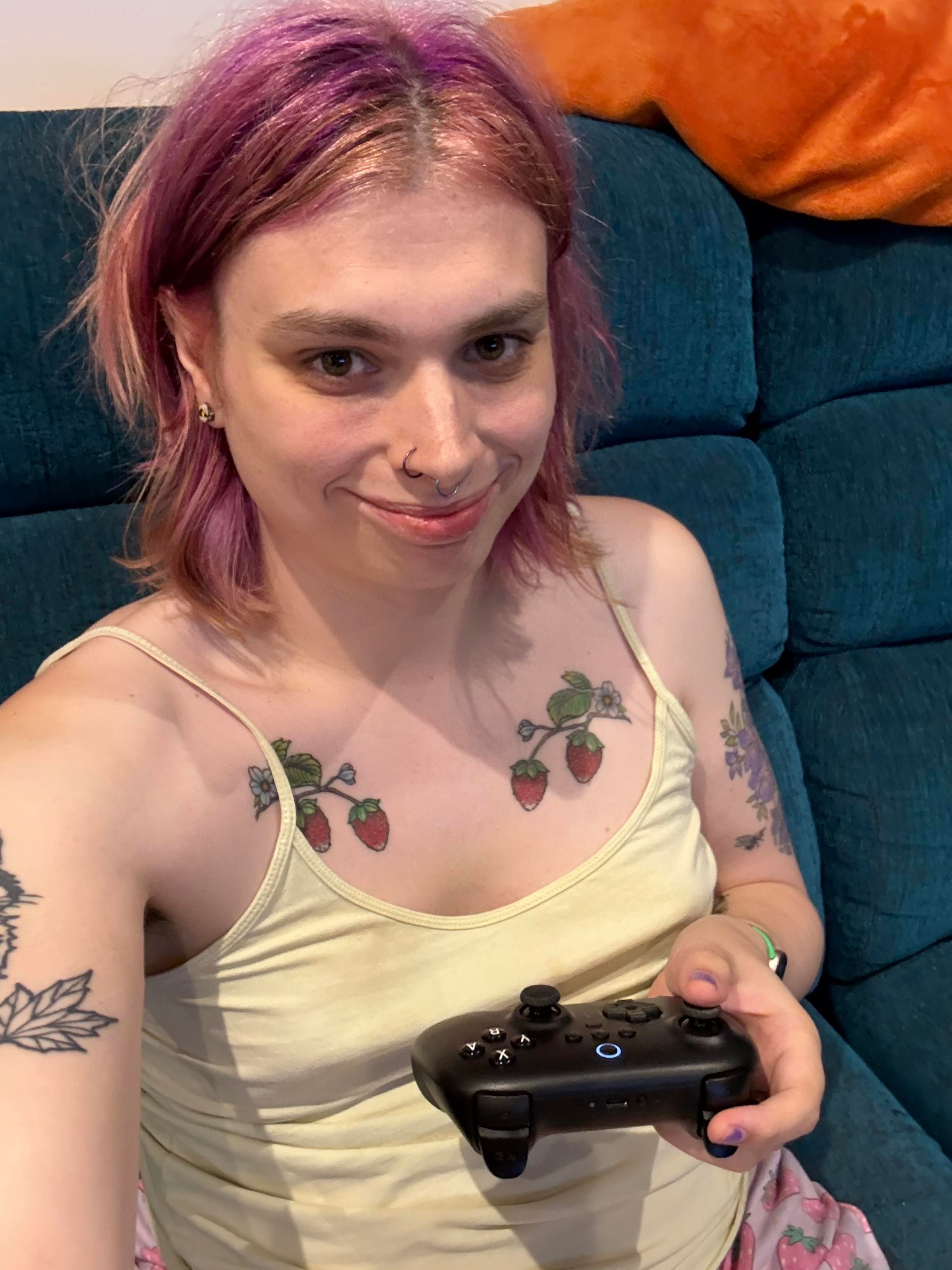 A selfie of liv sitting on the sofa holding an 8bitdo controller for the switch. She’s wearing a yellow camisole top.