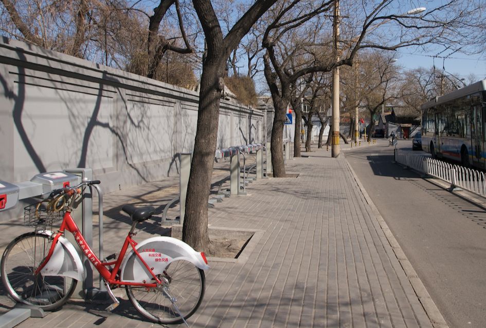 a pretty nice red bike sits astride a street. and maybe a bike lane? 