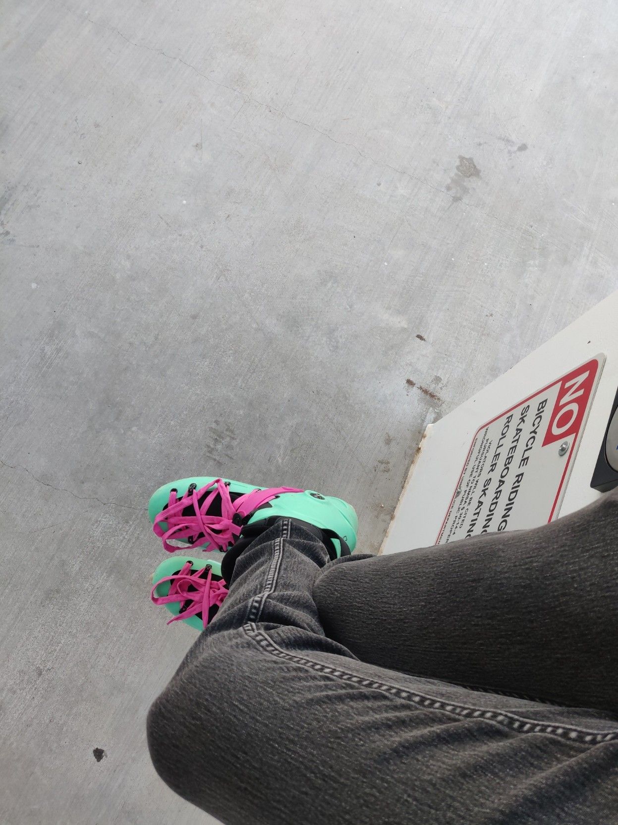 me sitting on a wall, wearing my skates, in front of a sign clearly stating "NO ROLLER SKATING"