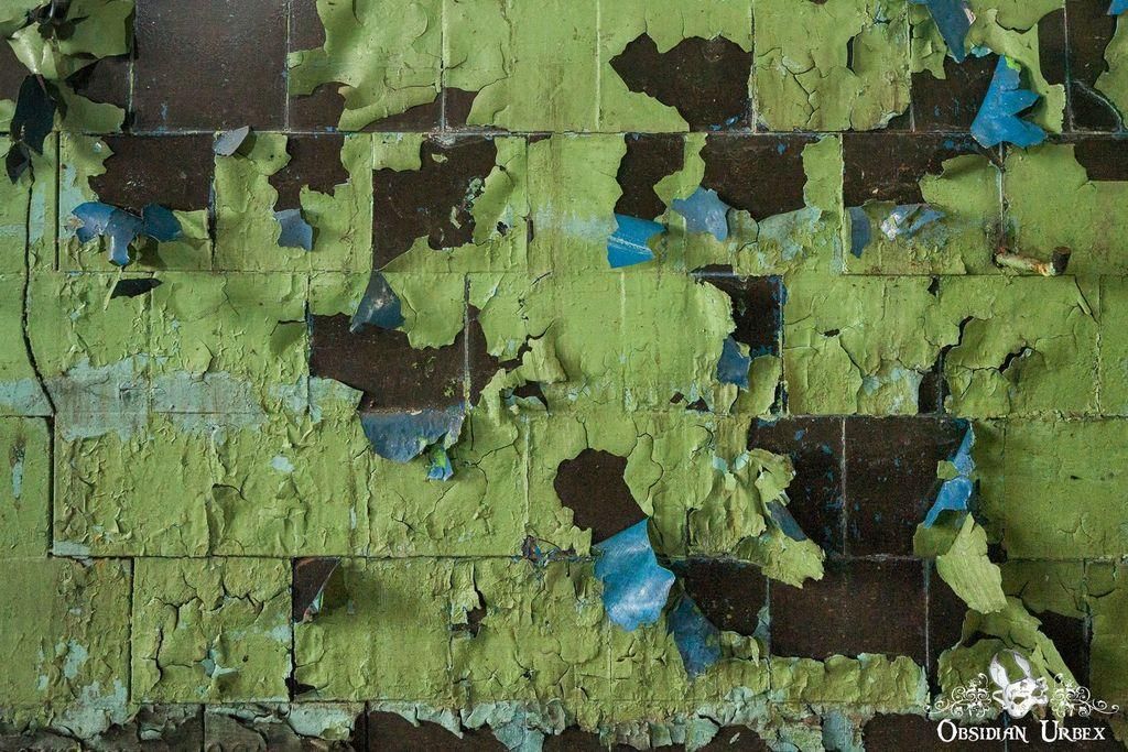 Distressed ceramic tiles are shown, with a flaking green painted surface, revealing a blue undercoat and black tile color.